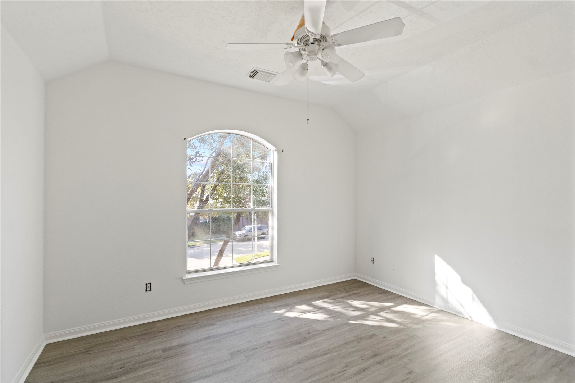 Bedroom 4 features vaulted ceilings, an elegant arched window, modern flooring, and abundant natural light, creating a bright and spacious retreat.