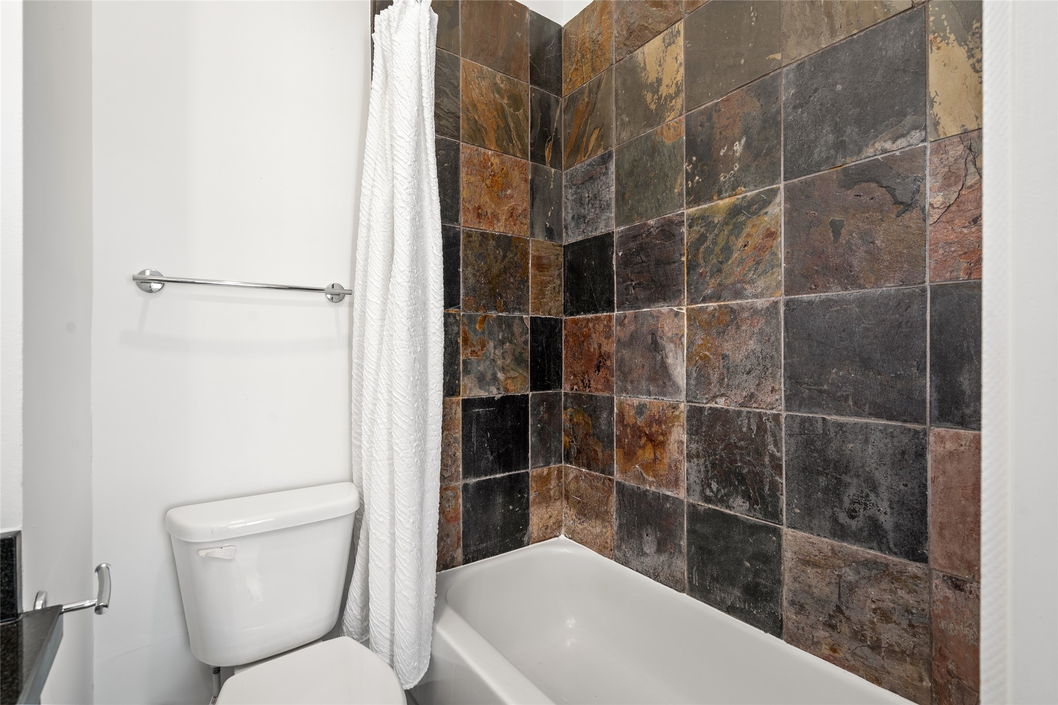Elegant primary bathroom featuring a tub/shower combo with gorgeous tilework, blending style and functionality