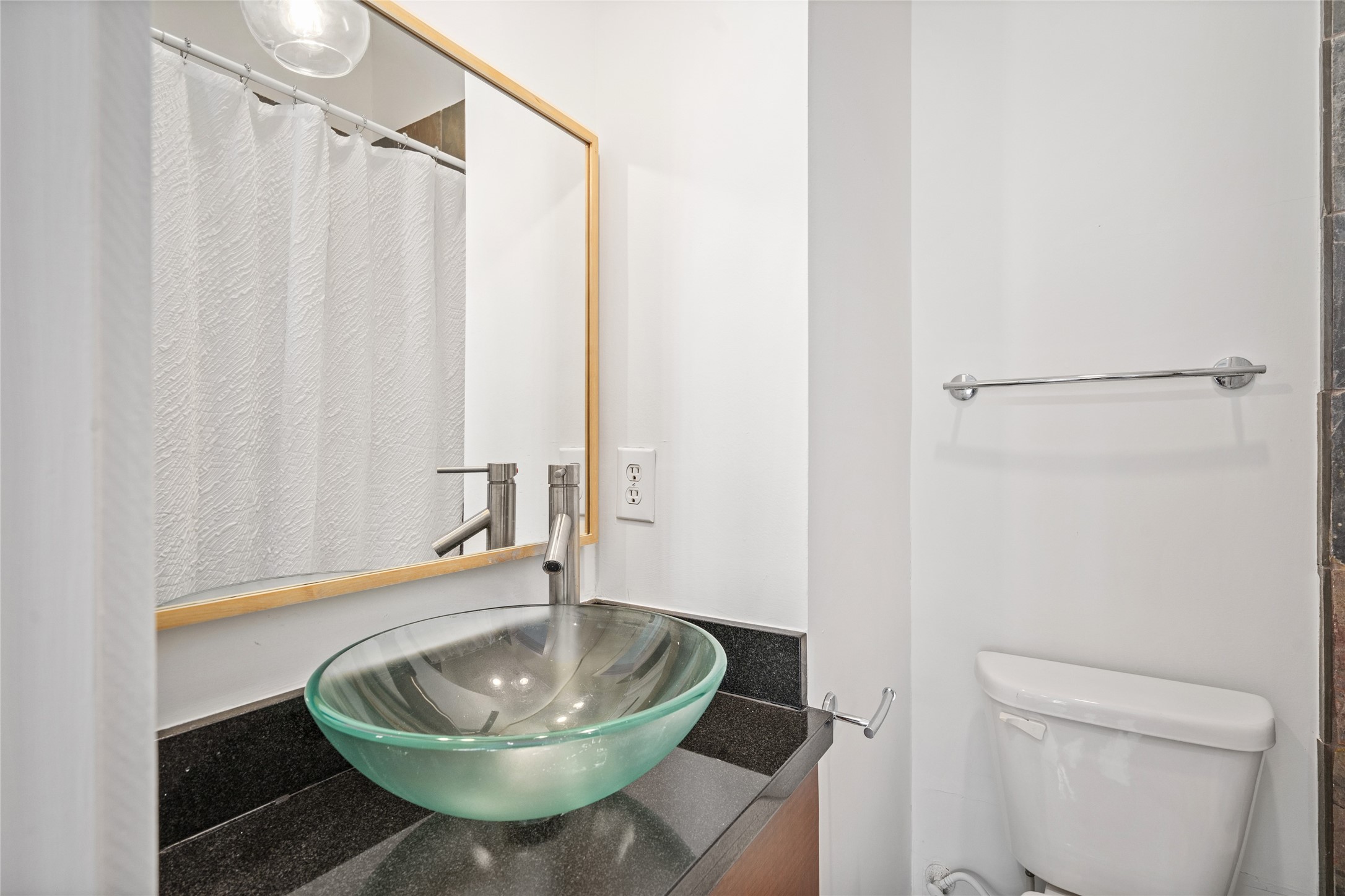 Stylish secondary bathroom featuring a unique glass sink, adding a modern touch and creating an elegant, contemporary look.