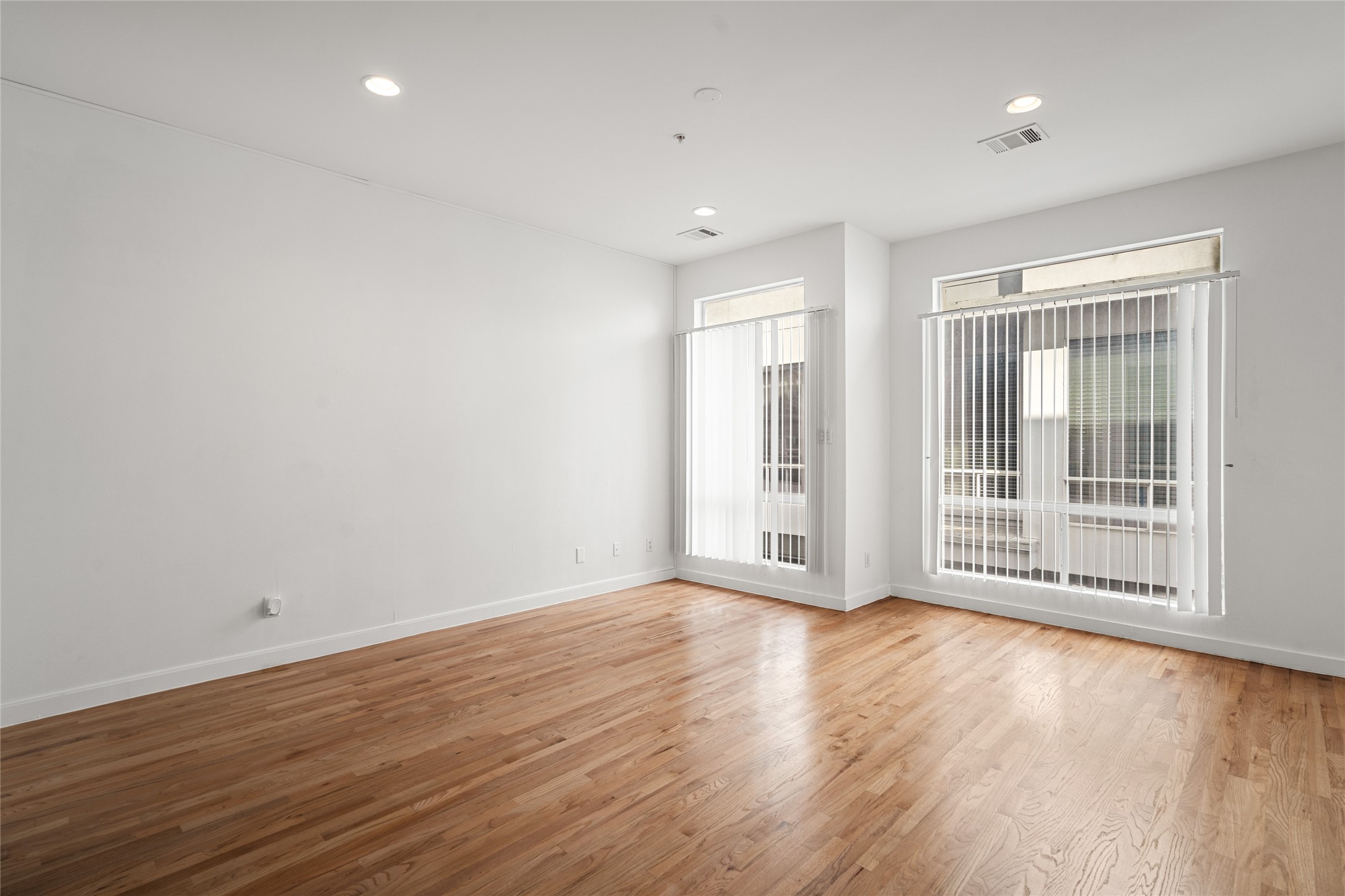 Spacious, well-lit, and airy living area enhanced by wide, floor-to-ceiling windows that flood the space with natural light, creating an inviting and open atmosphere.