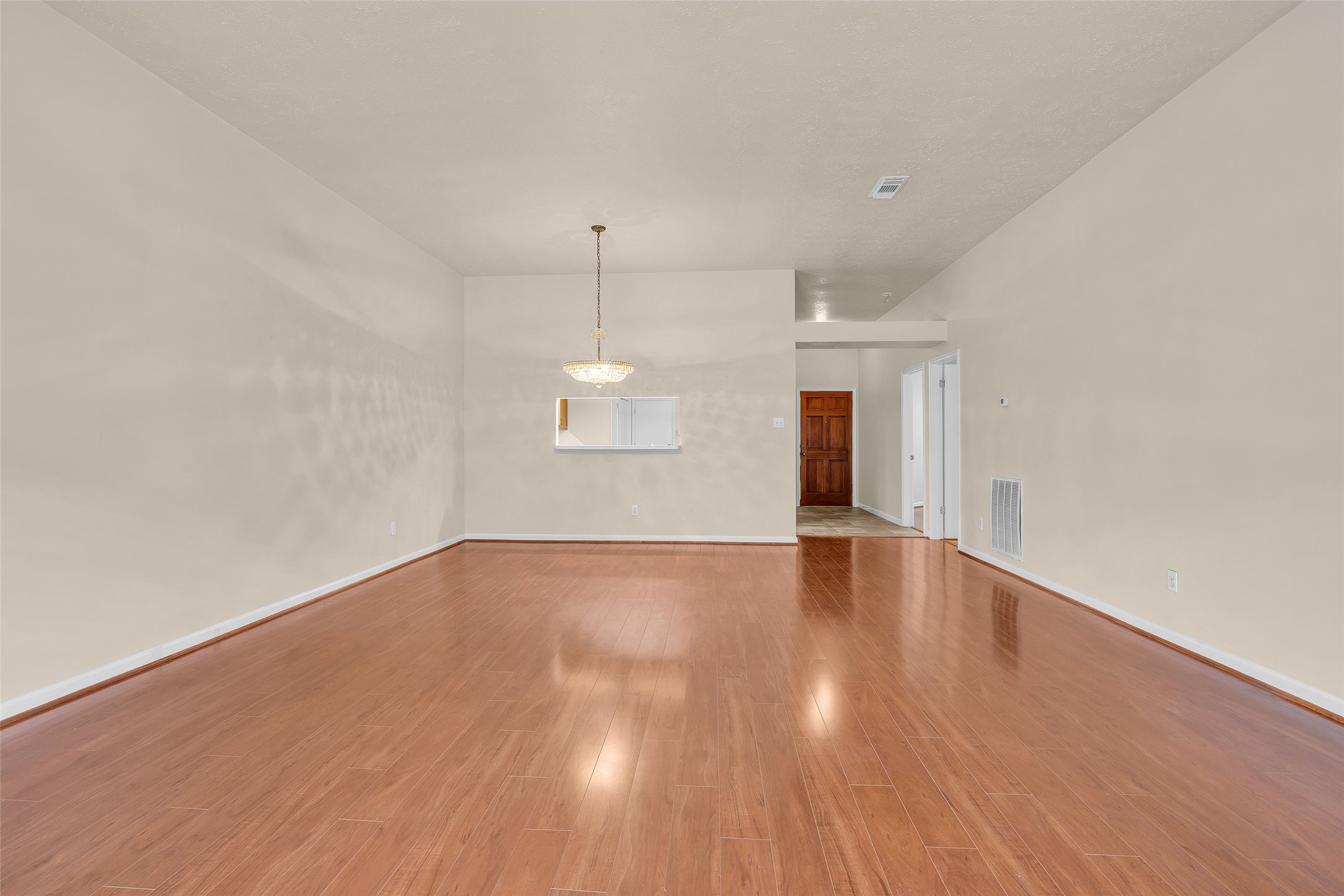 View of both the living and dining areas in an open layout, with a glimpse of the main entrance, highlighting a connected and welcoming flow throughout the main living space.