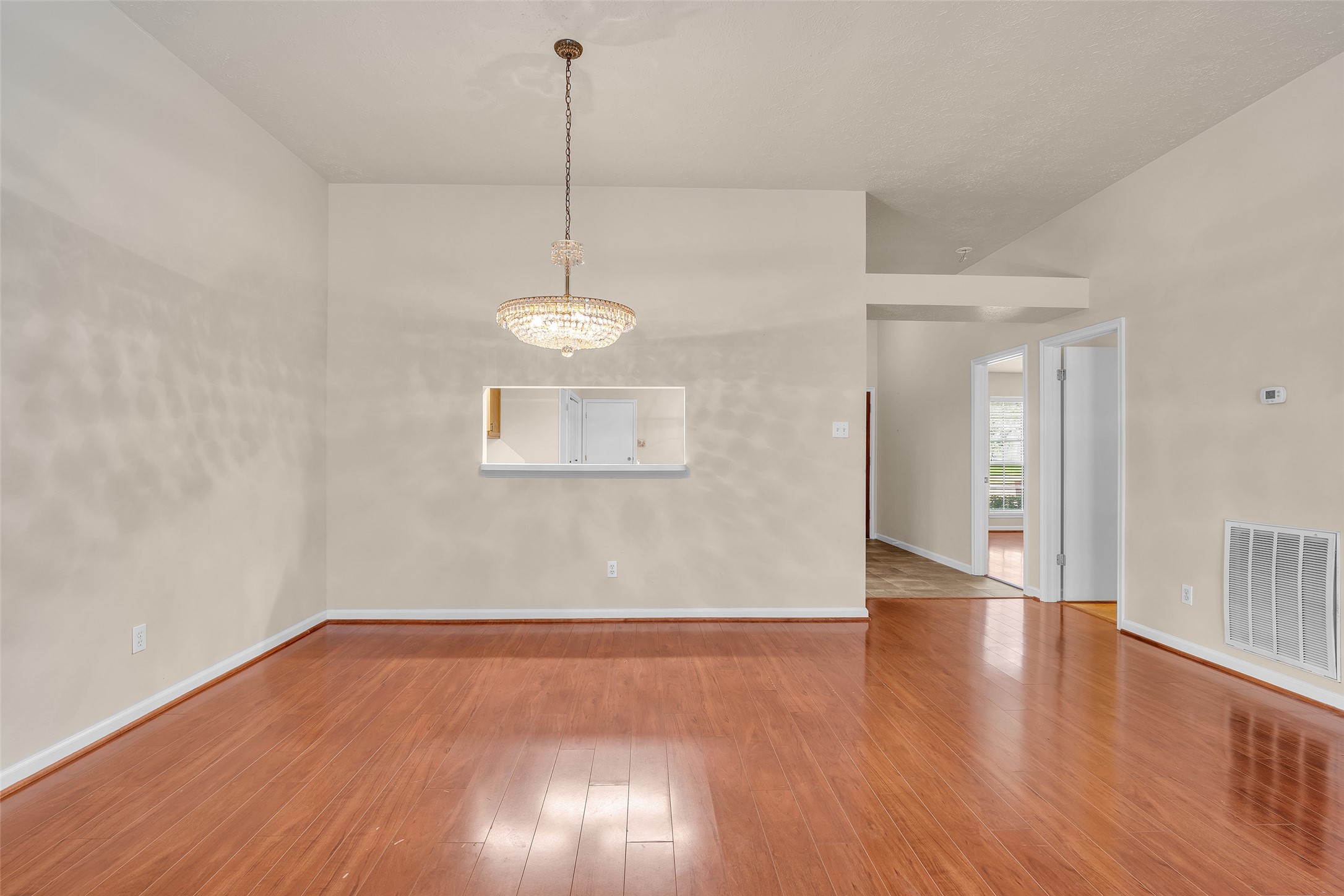 View of the dining area with continuous laminate flooring shared with the living room. Lighting features a crystal chandelier sourced from a Galveston estate.