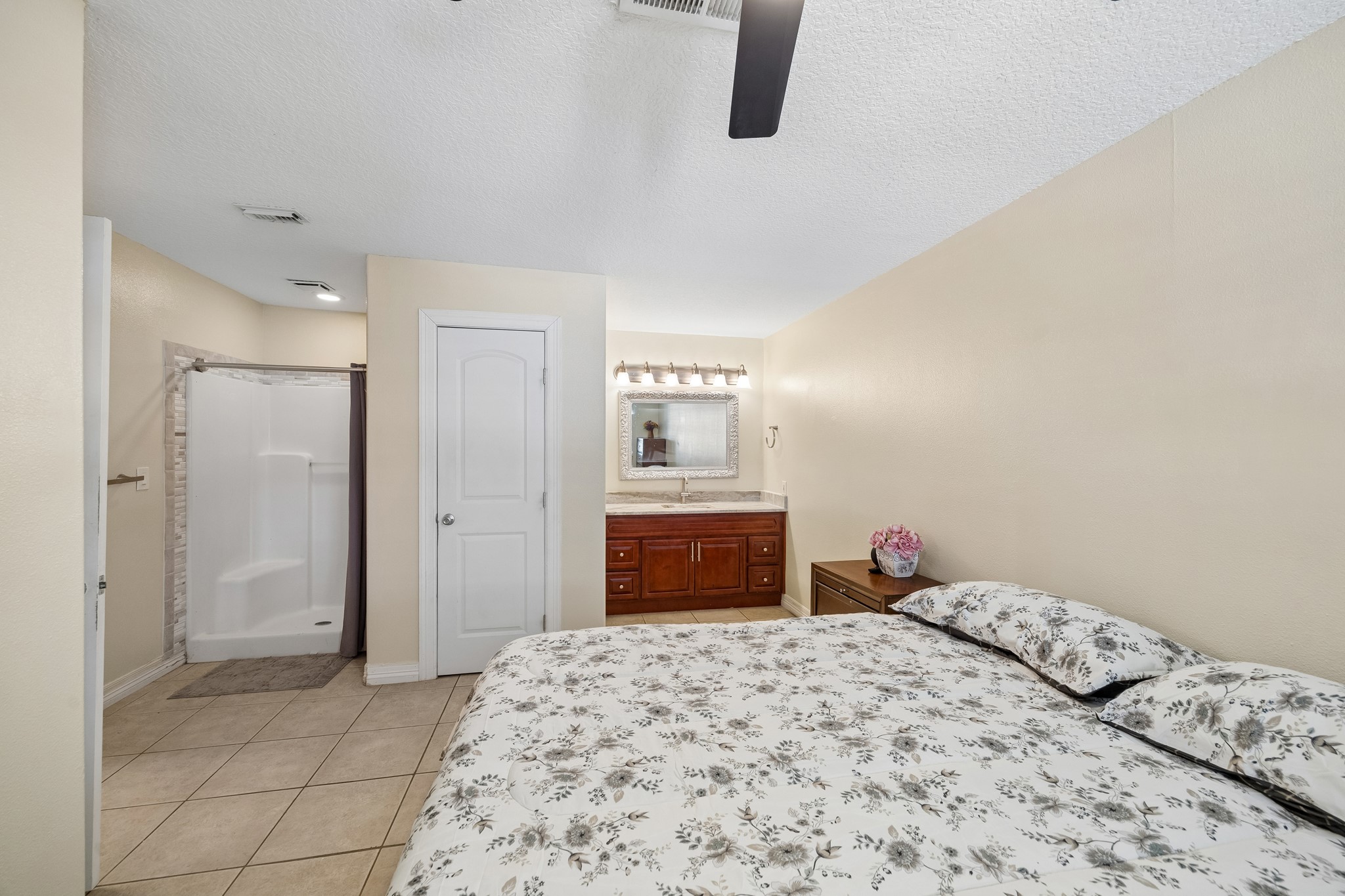 Cozy bedroom with an en-suite bathroom featuring a modern shower, elegant vanity, and ample natural light.