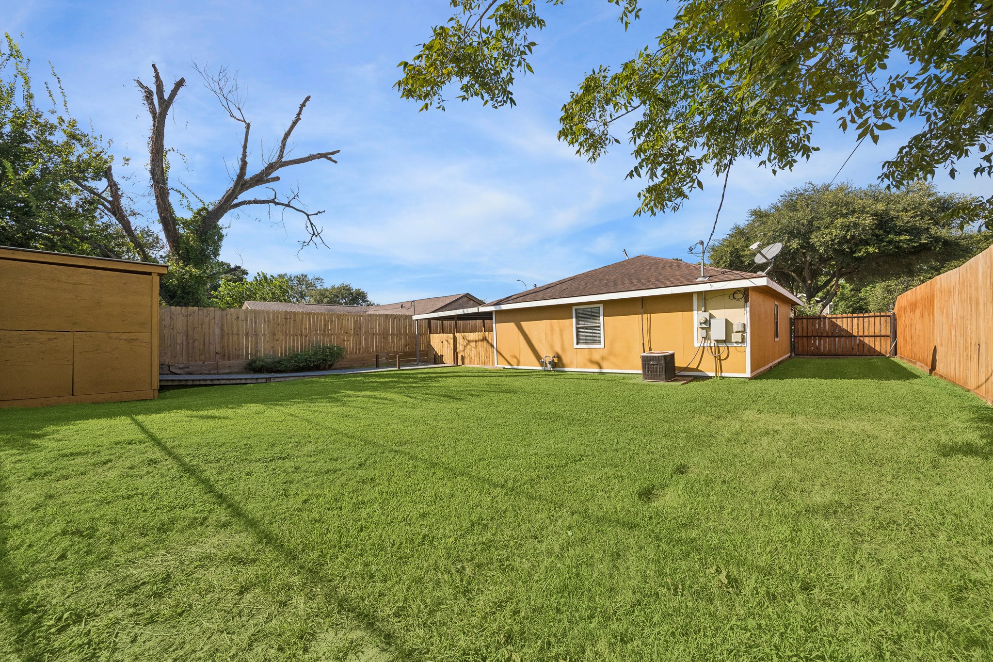 Expansive backyard with lush green lawn, privacy fencing, and mature trees, perfect for outdoor activities and relaxation.