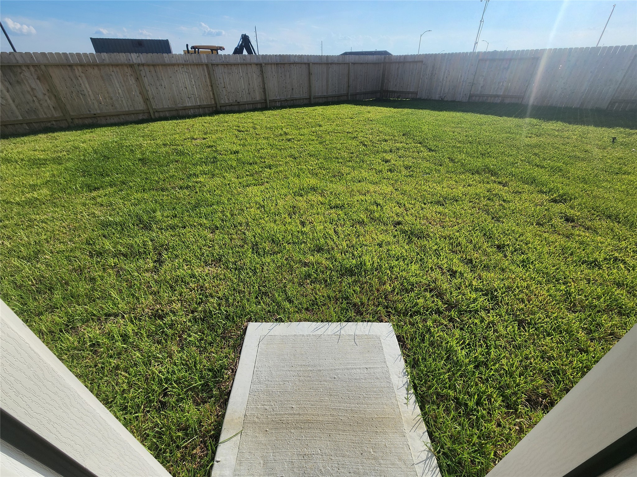 Spacious backyard with a well-maintained grassy lawn, enclosed by a wooden fence for privacy.