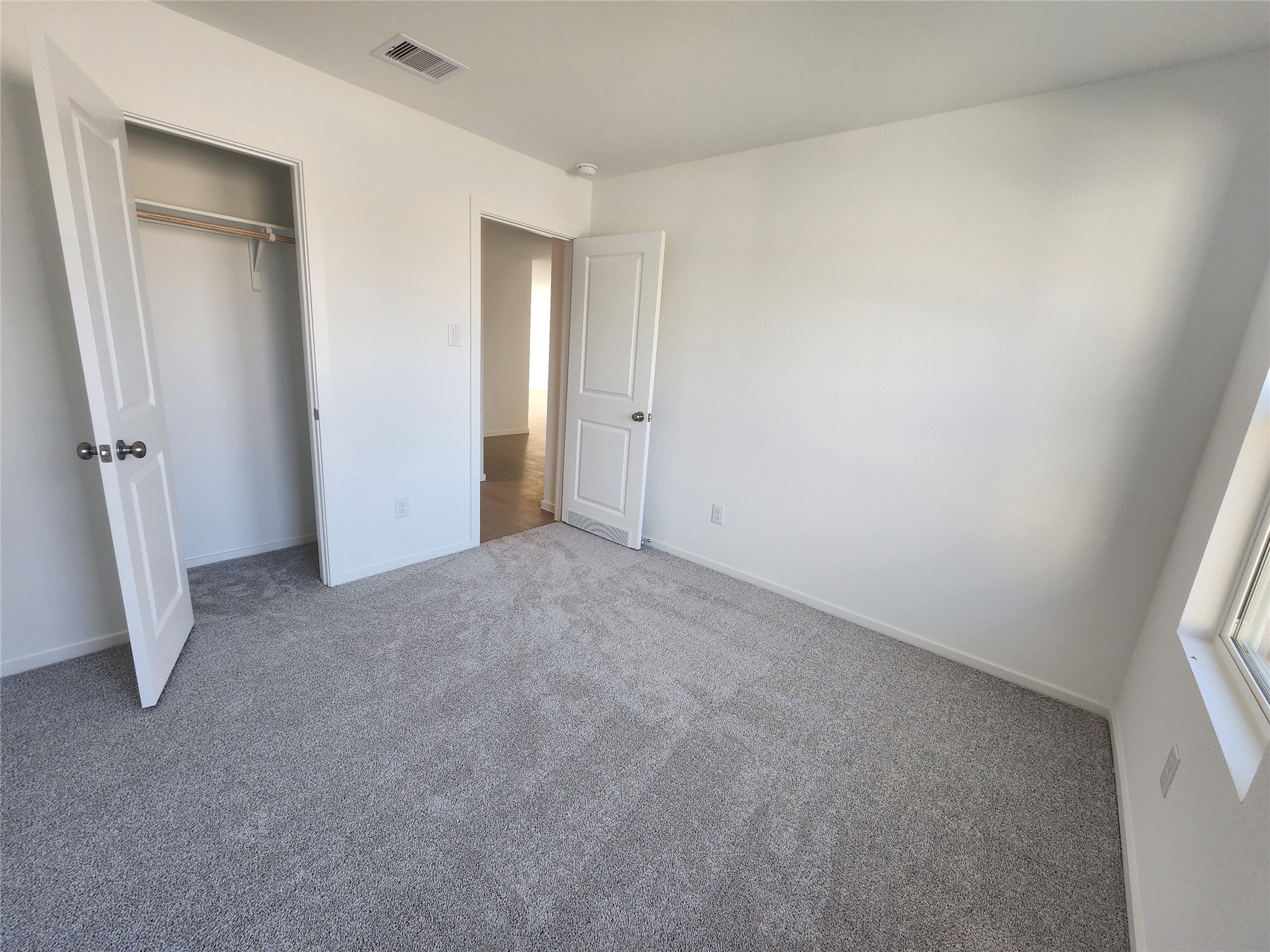 Bright secondary bedroom with recessed lighting and carpet.