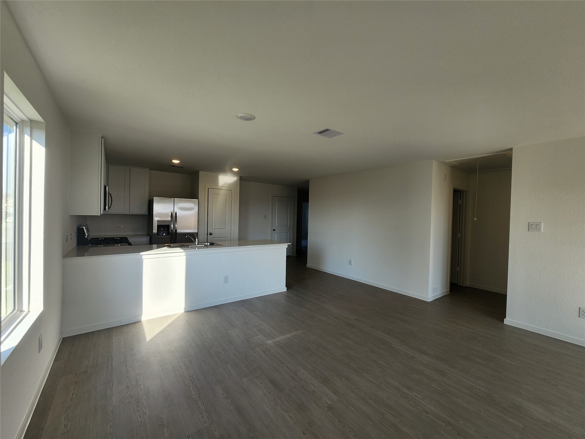 View of kitchen/living area  from backdoor. Entryway to the right leads to washer and dryer (included) as well as primary bedroom.