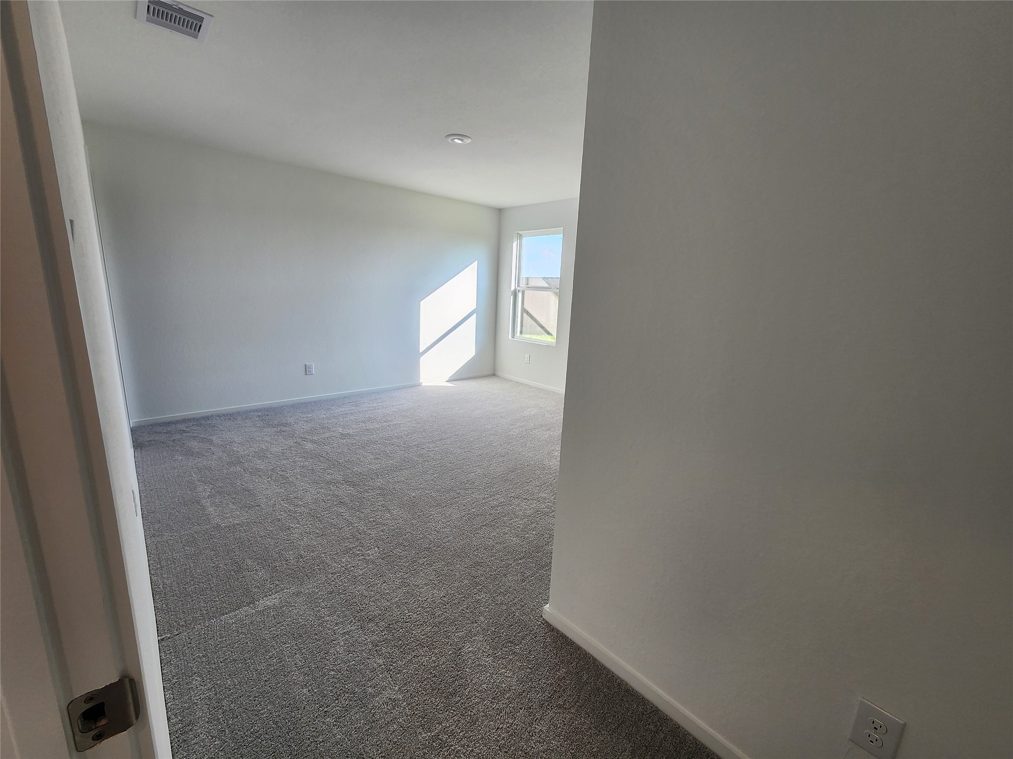 Entryway to primary bedroom with carpet and a window that lets in plenty of natural light, creating a warm and inviting atmosphere.