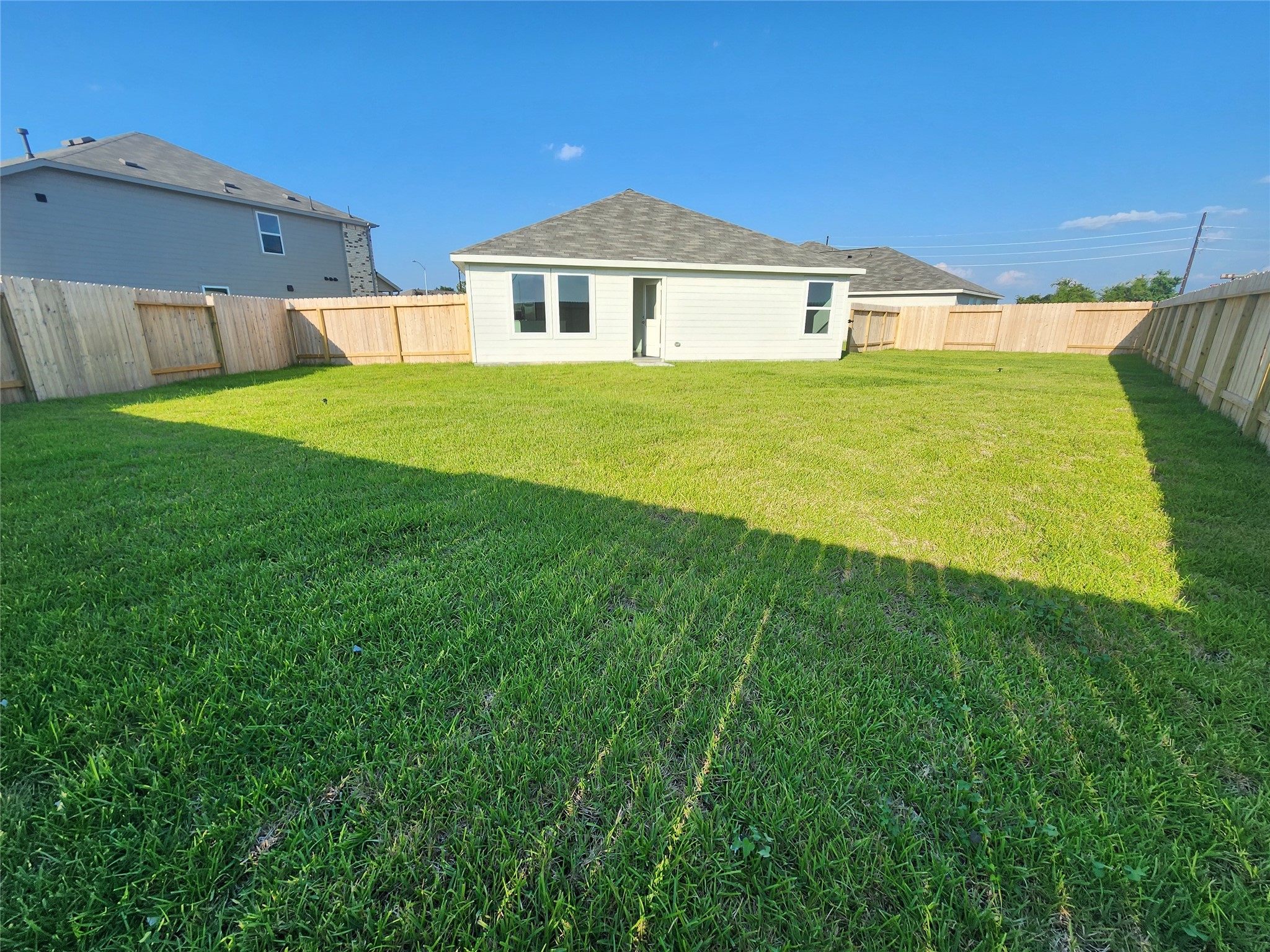 Spacious backyard with well-maintained lawn, bordered by a wooden privacy fence, perfect for outdoor activities.