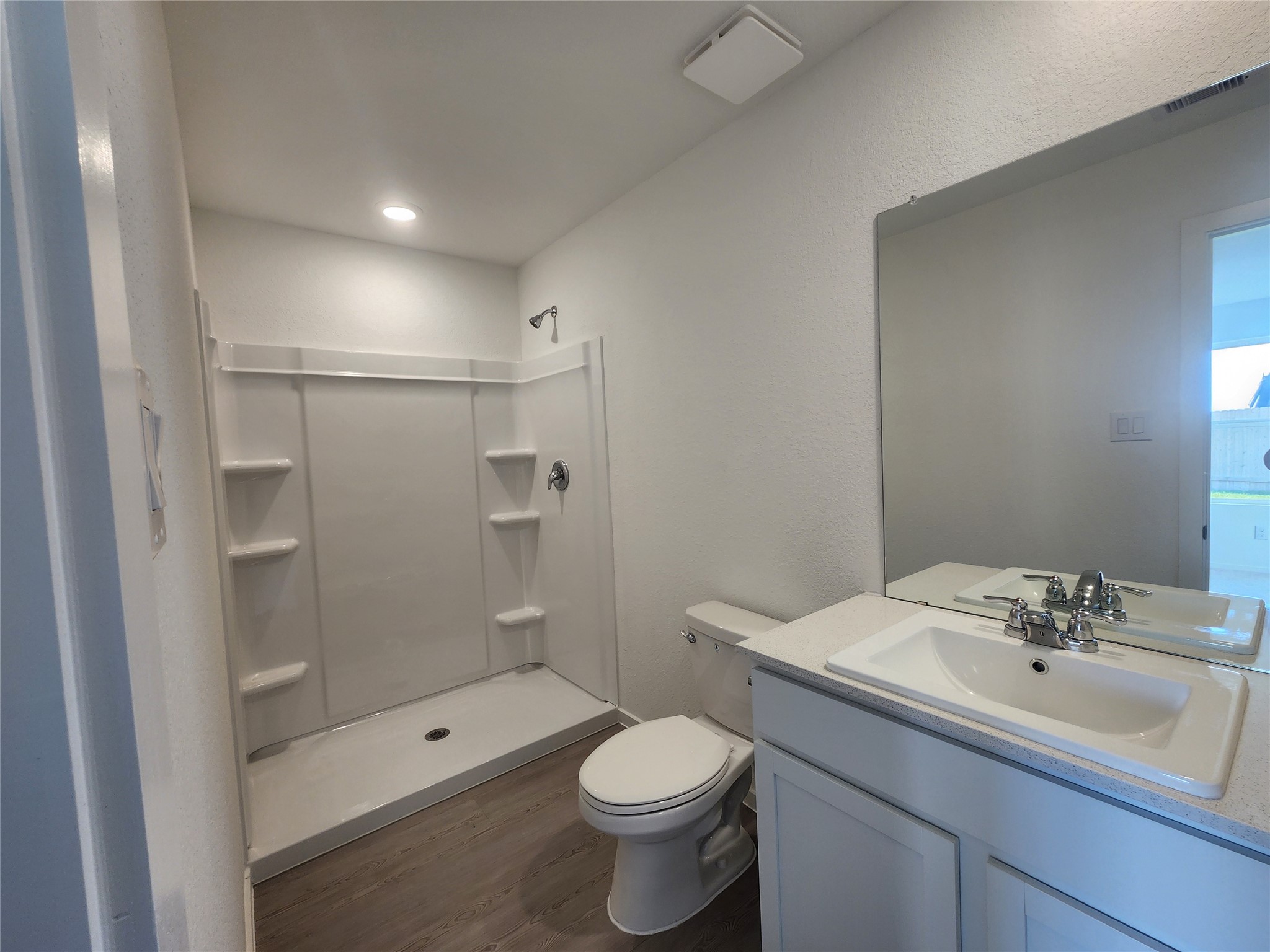 Modern  primary bathroom with a spacious walk-in shower, built in shelves, sleek fixtures, and a large mirror.