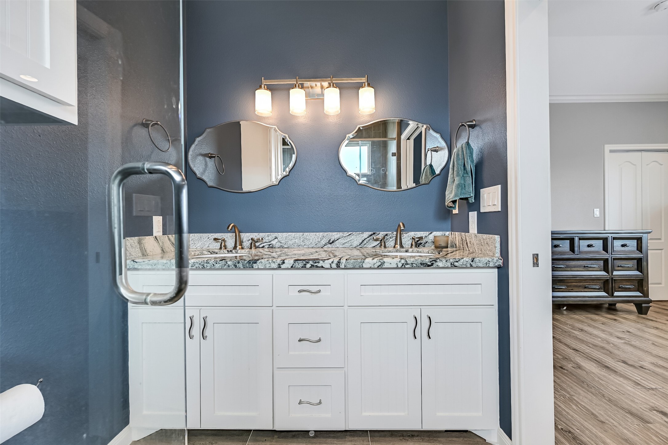 The vanity features beadboard accent shaker cabinetry, while undermount sinks and nickel fixtures completes the package.