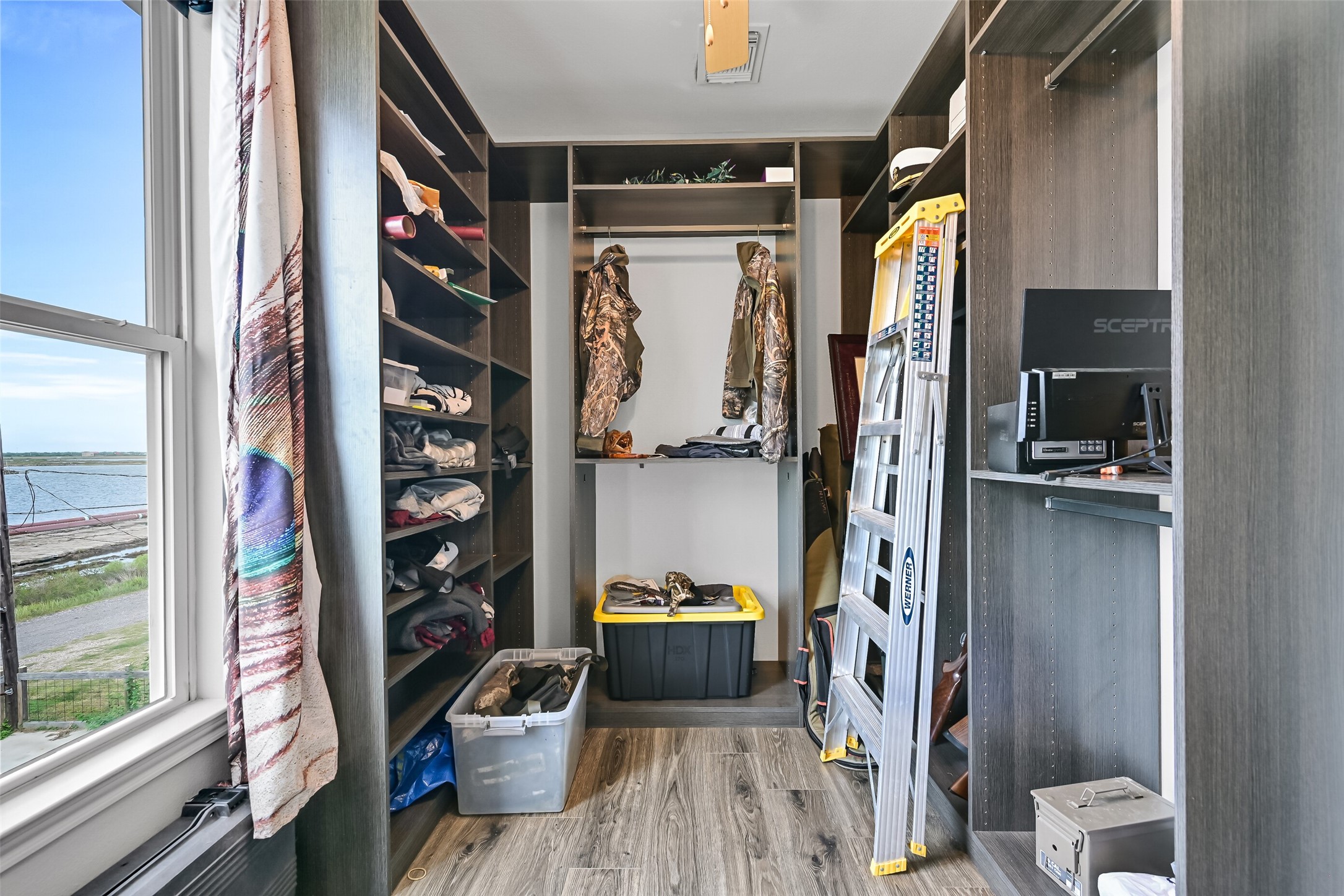 This is the smaller secondary bedroom, also with views of Highland Bayou. Currently it it utilized as storage with built-ins but could be removed and used as a traditional bedroom, or office space - your choice. Why don't we head back outside to explore the downstairs entertaining areas?