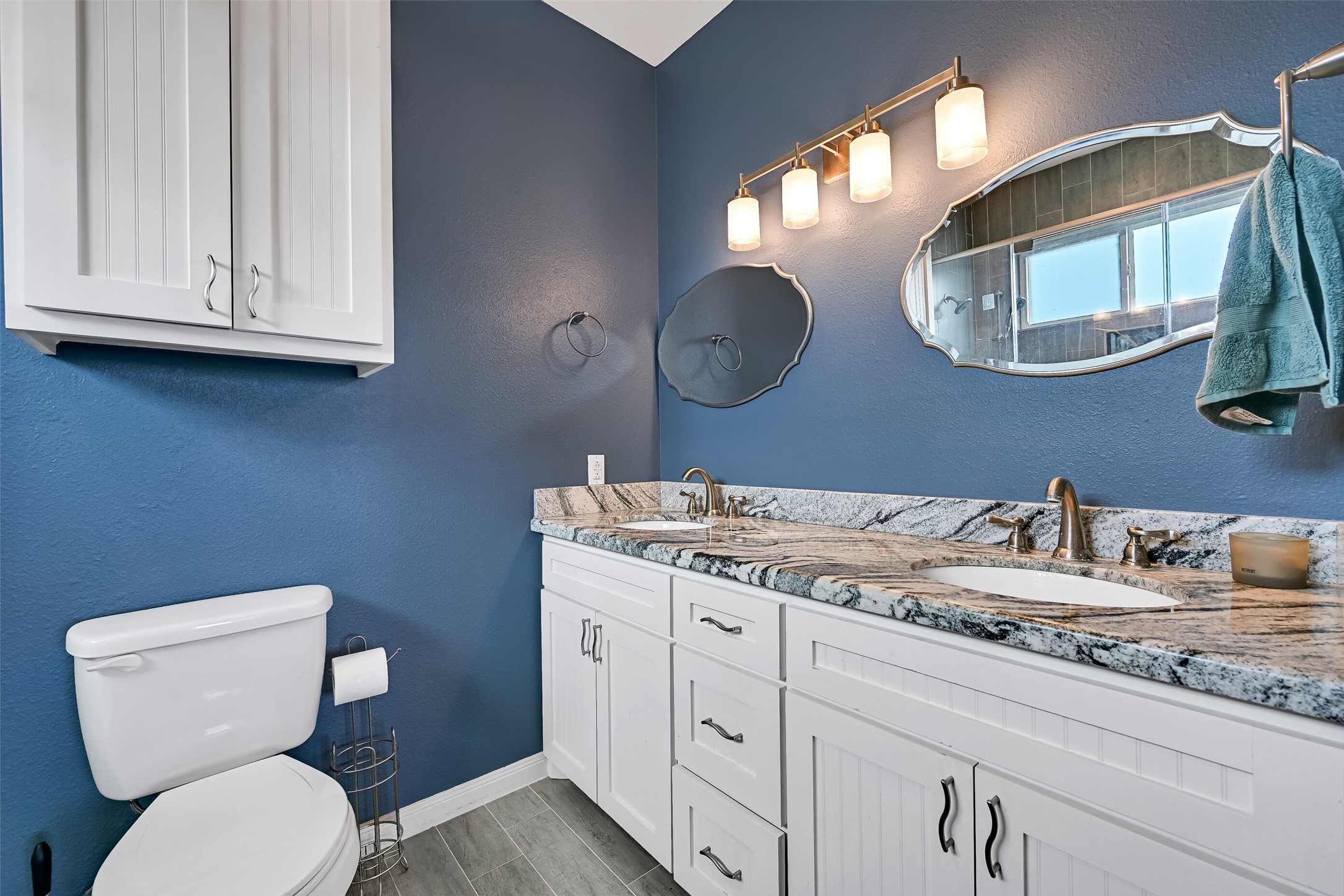 Primary bathroom featuring double sinks and the same luxurious granite surfaces found in the kitchen.