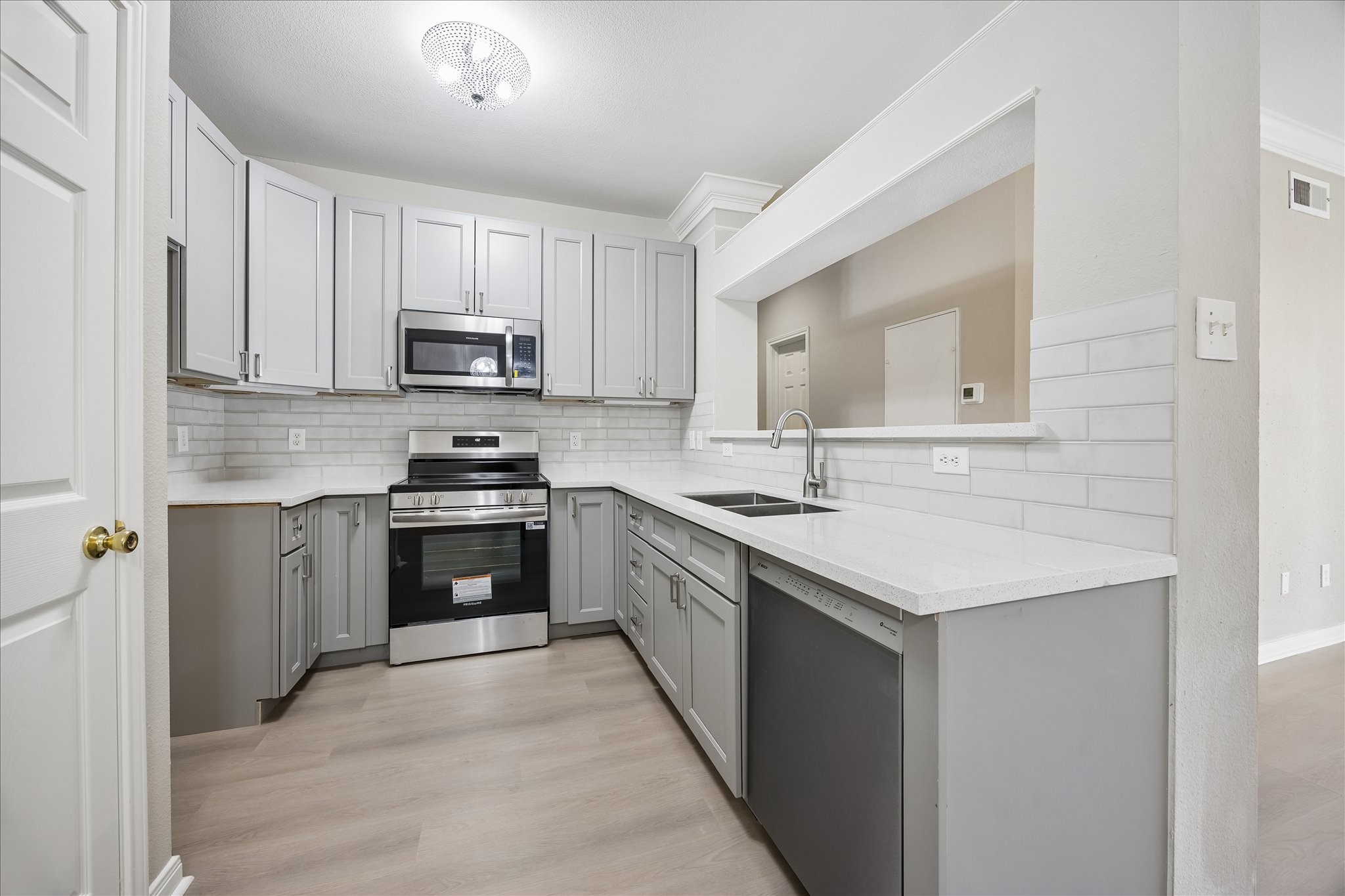Beautifully updated kitchen featuring white countertops, subway tile backsplash, gray shaker-style cabinetry w/ soft-close drawers & cabinets, brushed nickel hardware & stainless steel appliances. Fabulous combination of style & functionality! Generous countertop space & stainless steel appliances including Frigidaire electric range, built-in microwave & Bosch dishwasher. under-cabinet lighting, double-basin undermount stainless steel sink w/ gooseneck faucet & pantry closet w/ built-in shelving. Beautifully updated kitchen featuring white countertops, subway tile backsplash, gray shaker-style cabinetry w/ soft-close drawers & cabinets, brushed nickel hardware & stainless steel appliances. Fabulous combination of style & functionality! Generous countertop space & stainless steel appliances including Frigidaire electric range, built-in microwave & Bosch dishwasher. under-cabinet lighting, double-basin undermount stainless steel sink w/ gooseneck faucet & pantry closet w/ built-in shelving.