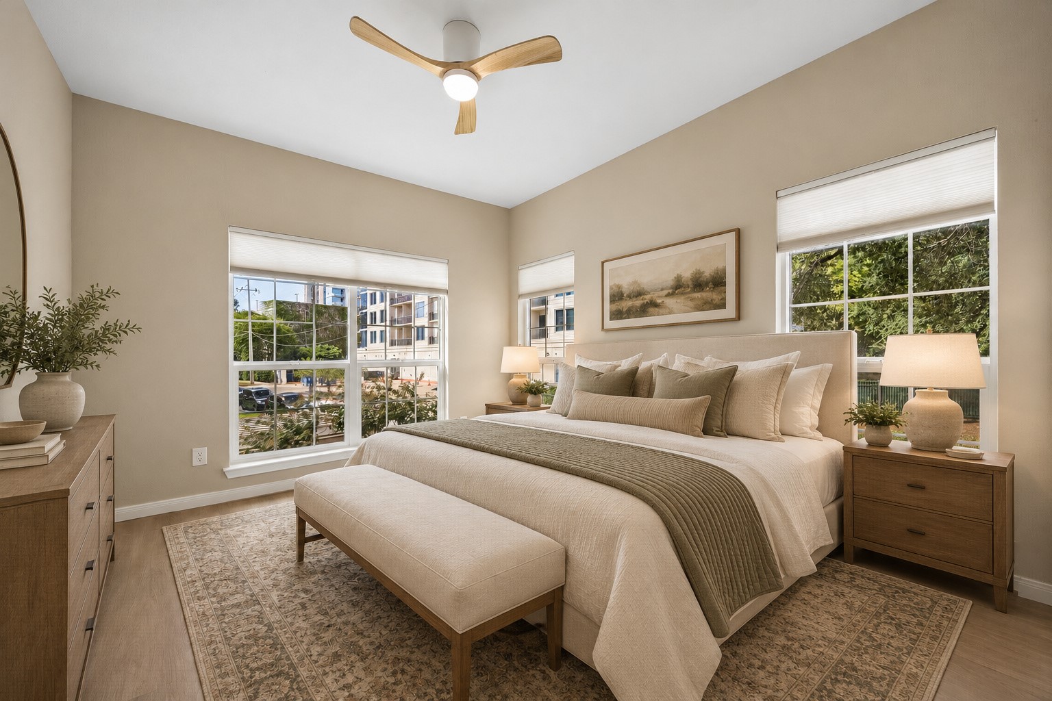 Spacious updated primary bedroom featuring new LVT flooring, a new ceiling fan w/ light & three large windows offering abundant natural light. Generous space for a king-sized bed & additional furnishings.  Lovely views of the landscaped community grounds create a peaceful retreat! Not shown isa generous primary walk-in closet featuring extensive custom shelving, hanging rods & convenient pull-out storage drawers. Wonderful storage & organization! Photo is virtually stage.