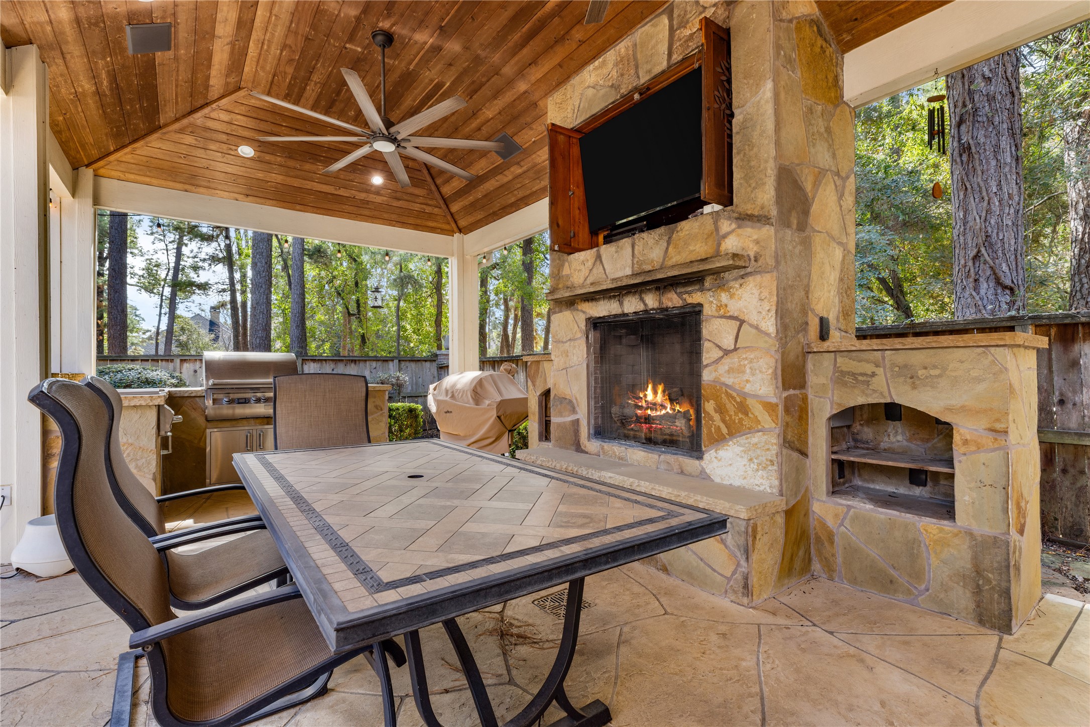 Outdoor living area with TV included and outdoor speakers. Fireplace fire has been digitally added for illustrative purposes.
