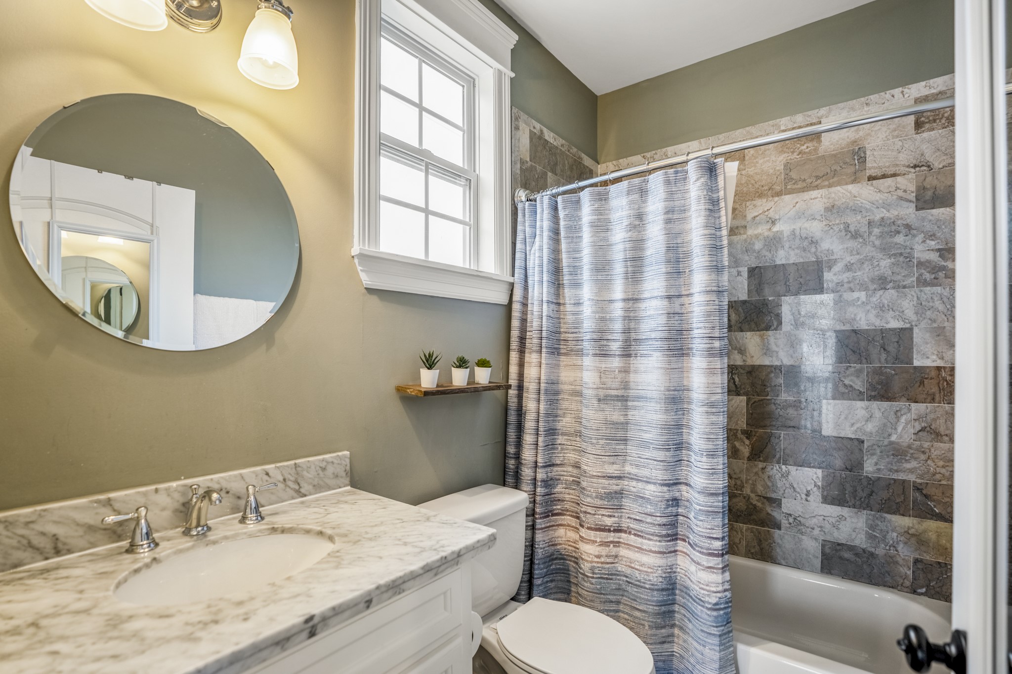 Full bathroom with marble counters and a tub in this garage apartment.