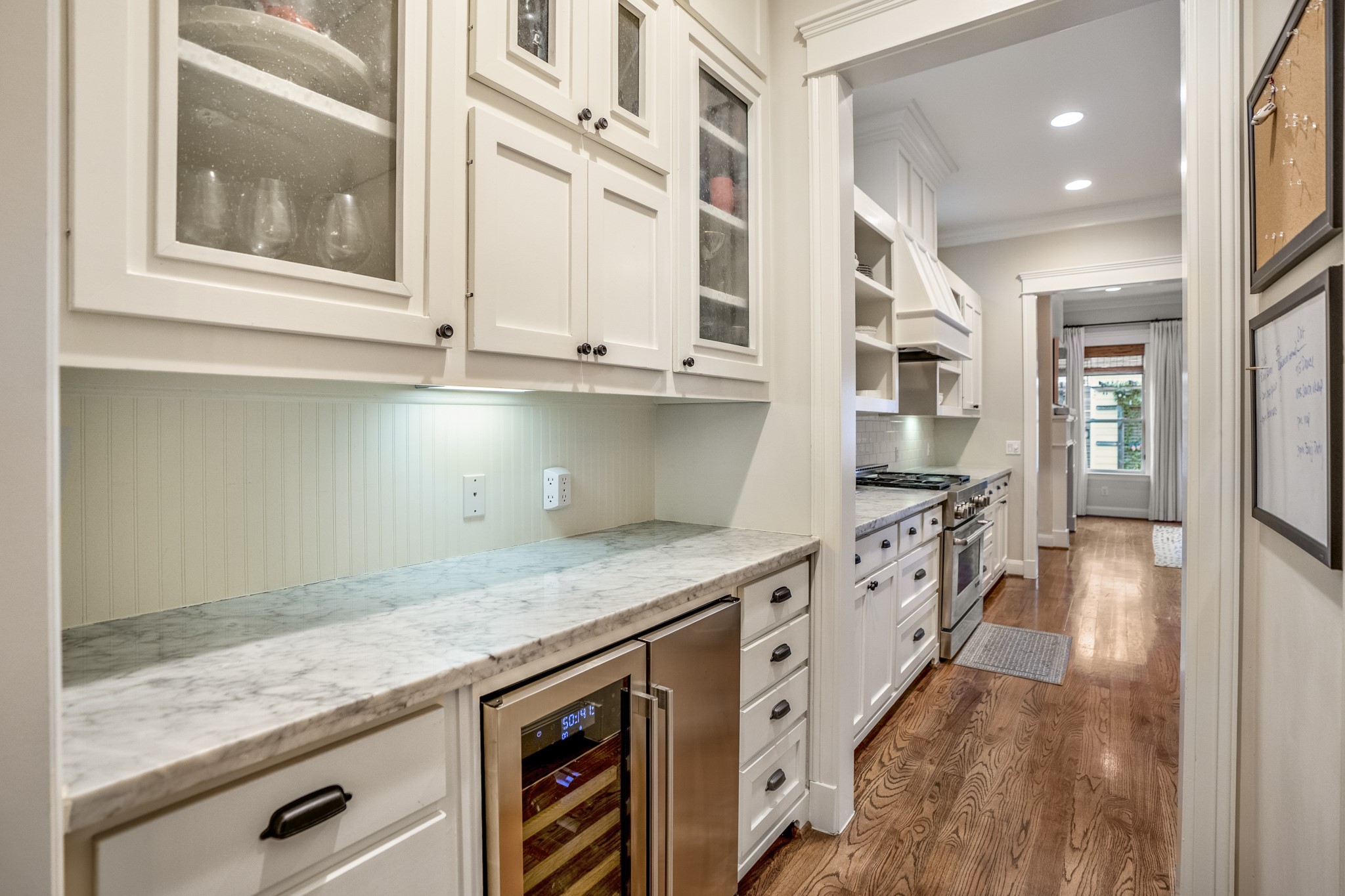 A closer look at the butler's pantry with a beverage fridge, under cabinet lighting, and more cabinets for storage.