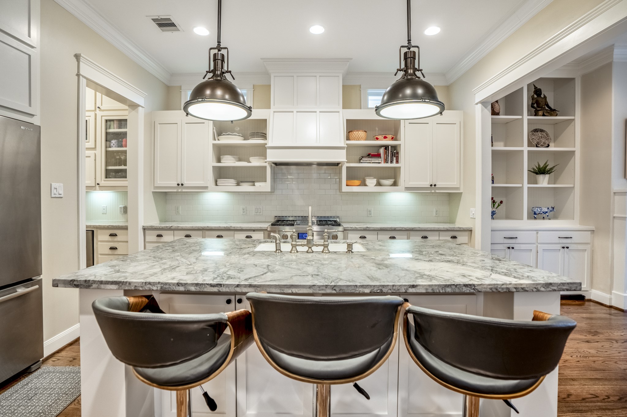 An adorable island with pendant lighting and seating for three. Neutral and classic color scheme in this home.