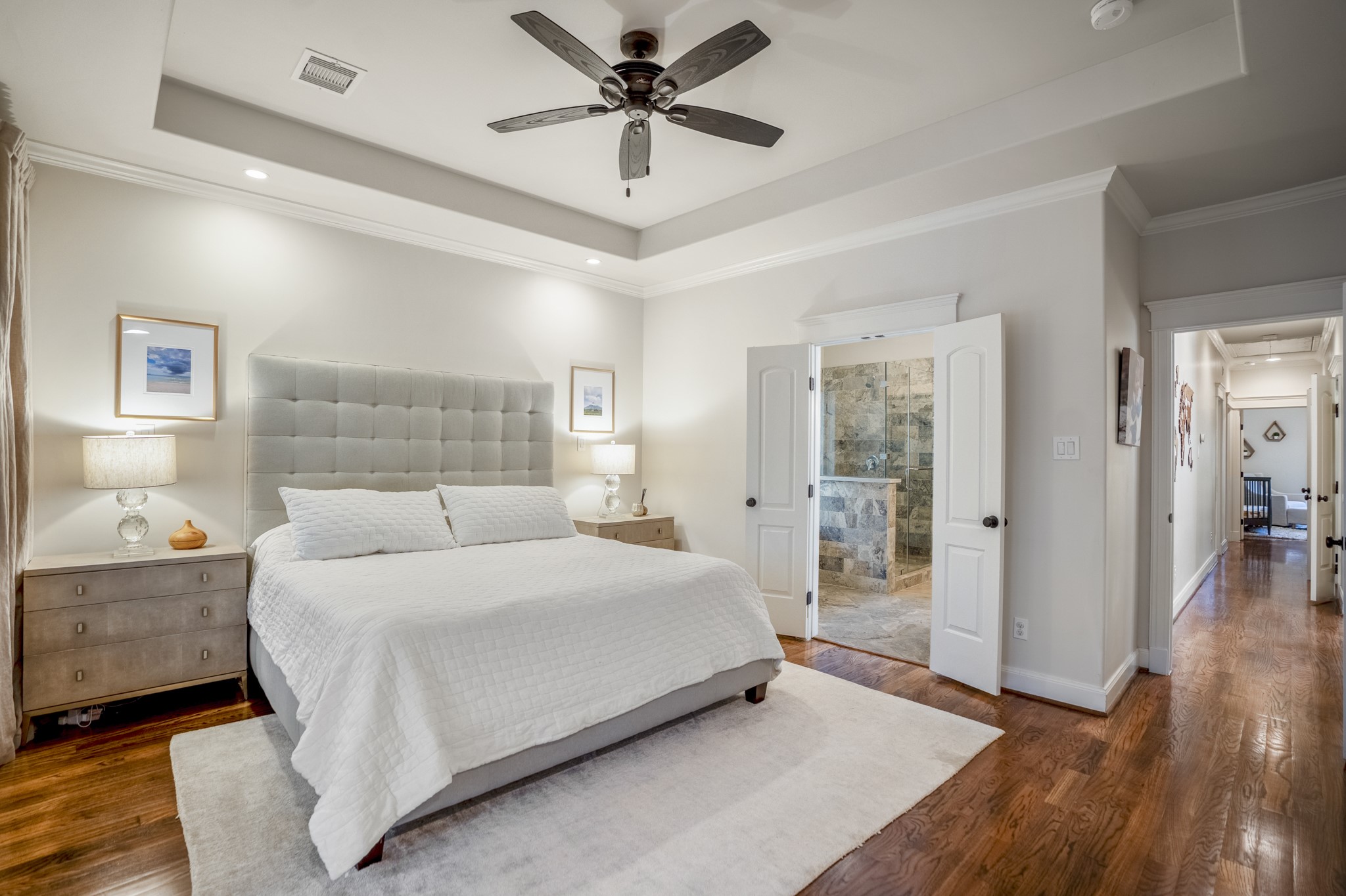 Primary bedroom in relation to the bathroom. Tray ceiling accents and a ceiling fan in your sanctuary.