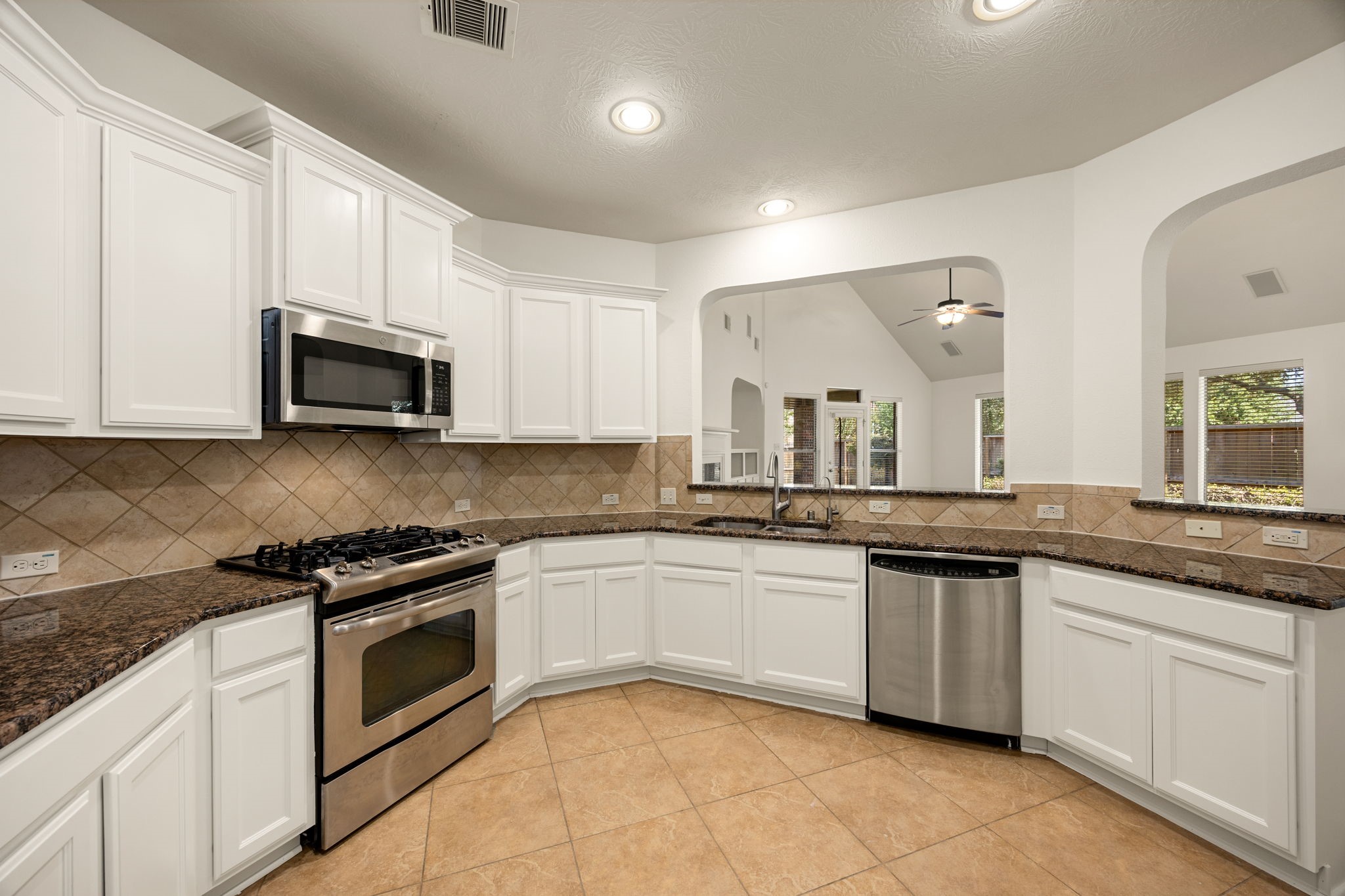 Positioned perfectly at the very center of the home, this unique circular kitchen offers a highly functional, wrapping design that serves as the ultimate hub for daily life. The sleek stainless steel gas range and matching built-in microwave provides modern cooking efficiency.