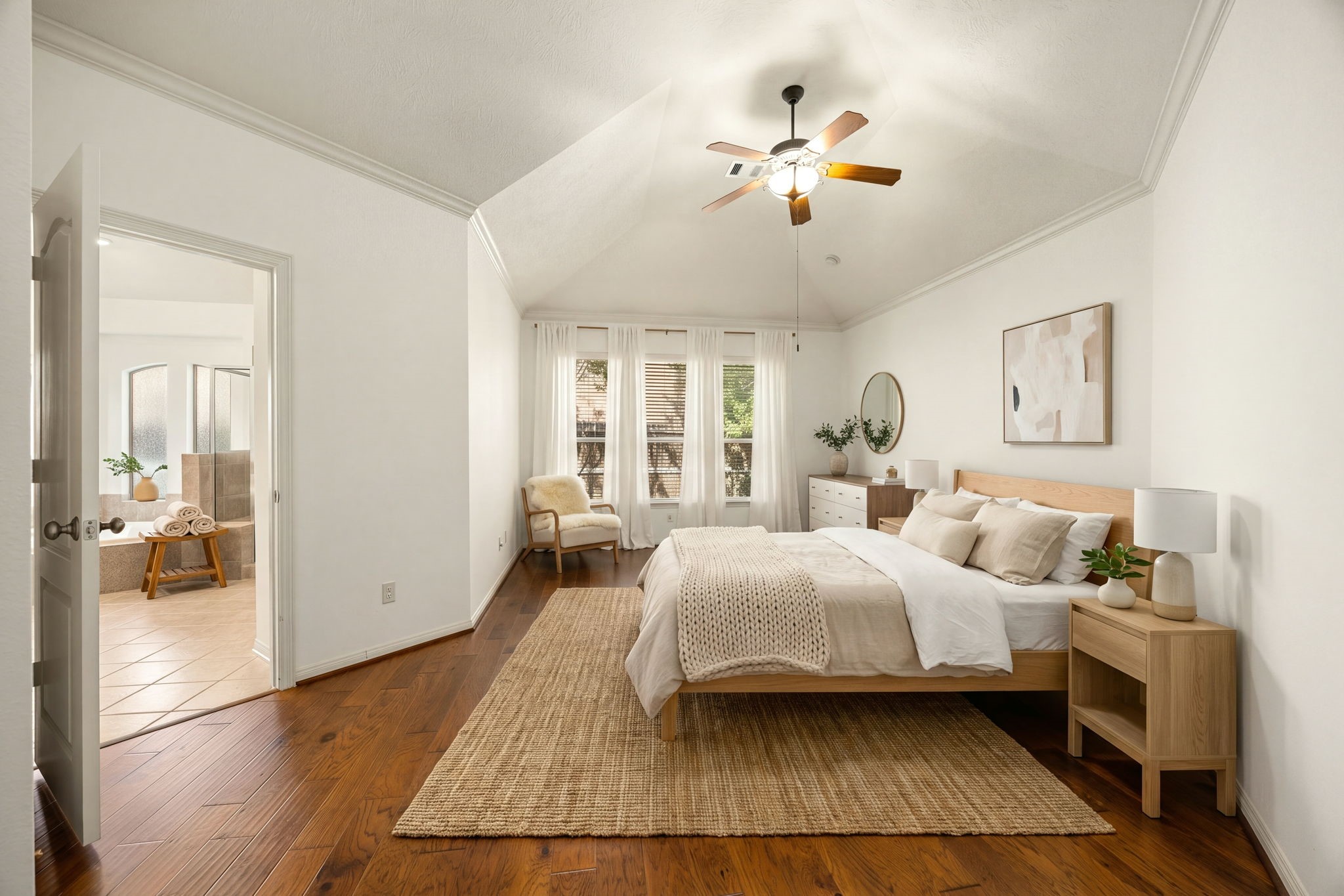 This expansive primary suite serves as a luxurious private sanctuary, crowned by a high tray ceiling with crown molding and anchored by rich hardwood flooring. The beautiful wall of triple windows overlooks the backyard greenery, bathing the entire room in soft natural light while maintaining a peaceful, tucked-away ambiance. *Virtually Staged