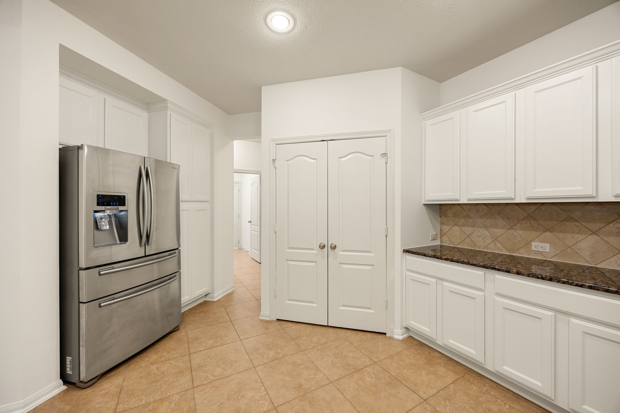 Completing the circular kitchen layout, this final angle highlights an expansive double-door pantry alongside a generous built-in serving station.