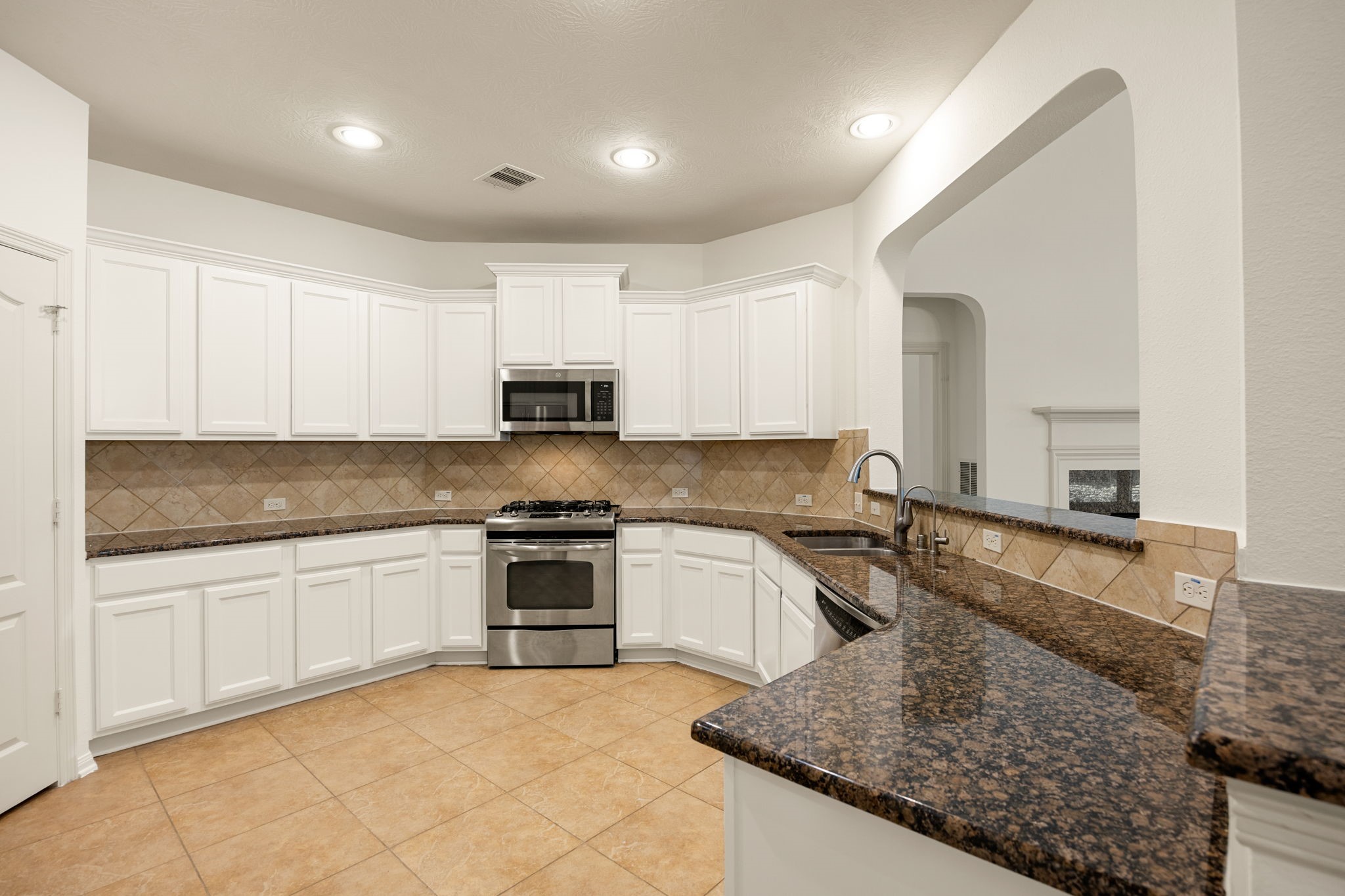 This beautifully designed kitchen combines bright, open space with exceptional functionality, featuring an abundance of crisp white cabinetry and expansive granite countertops.
