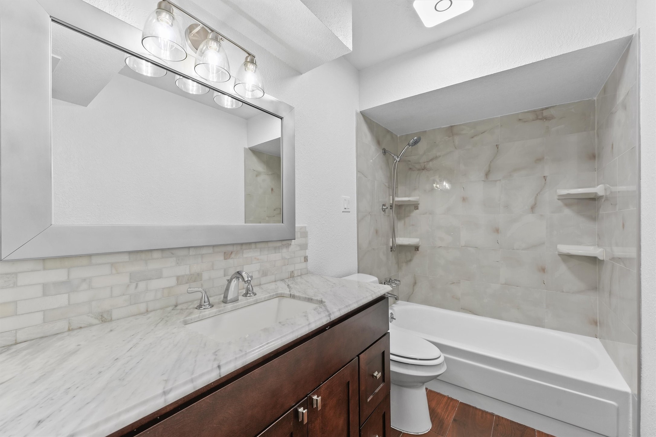 Primary bathroom - totally renovated with updated countertop, light fixture and mirror, toilet, and tub/shower combo
