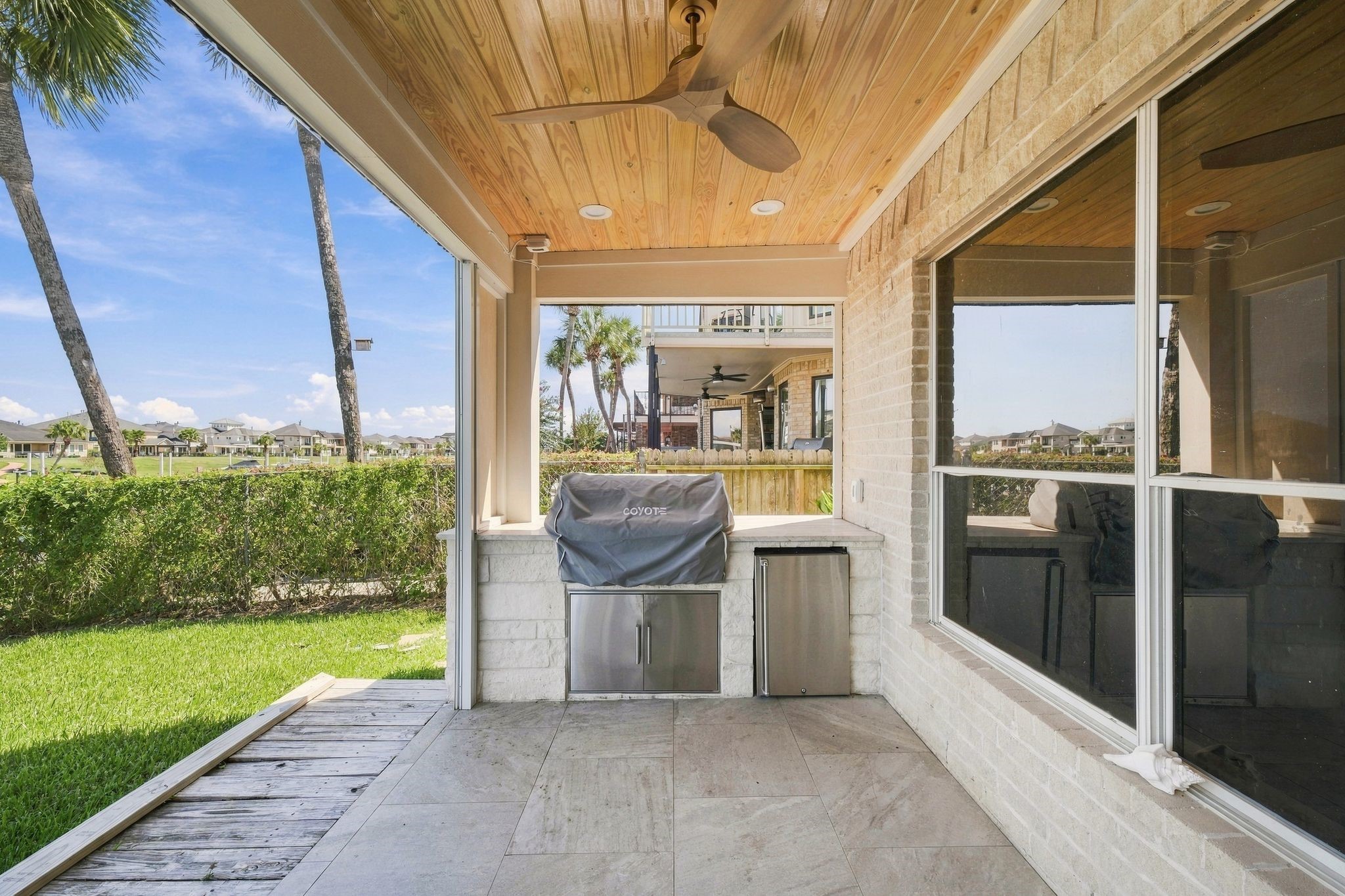The covered patio features an outdoor kitchen with a built-in grill.