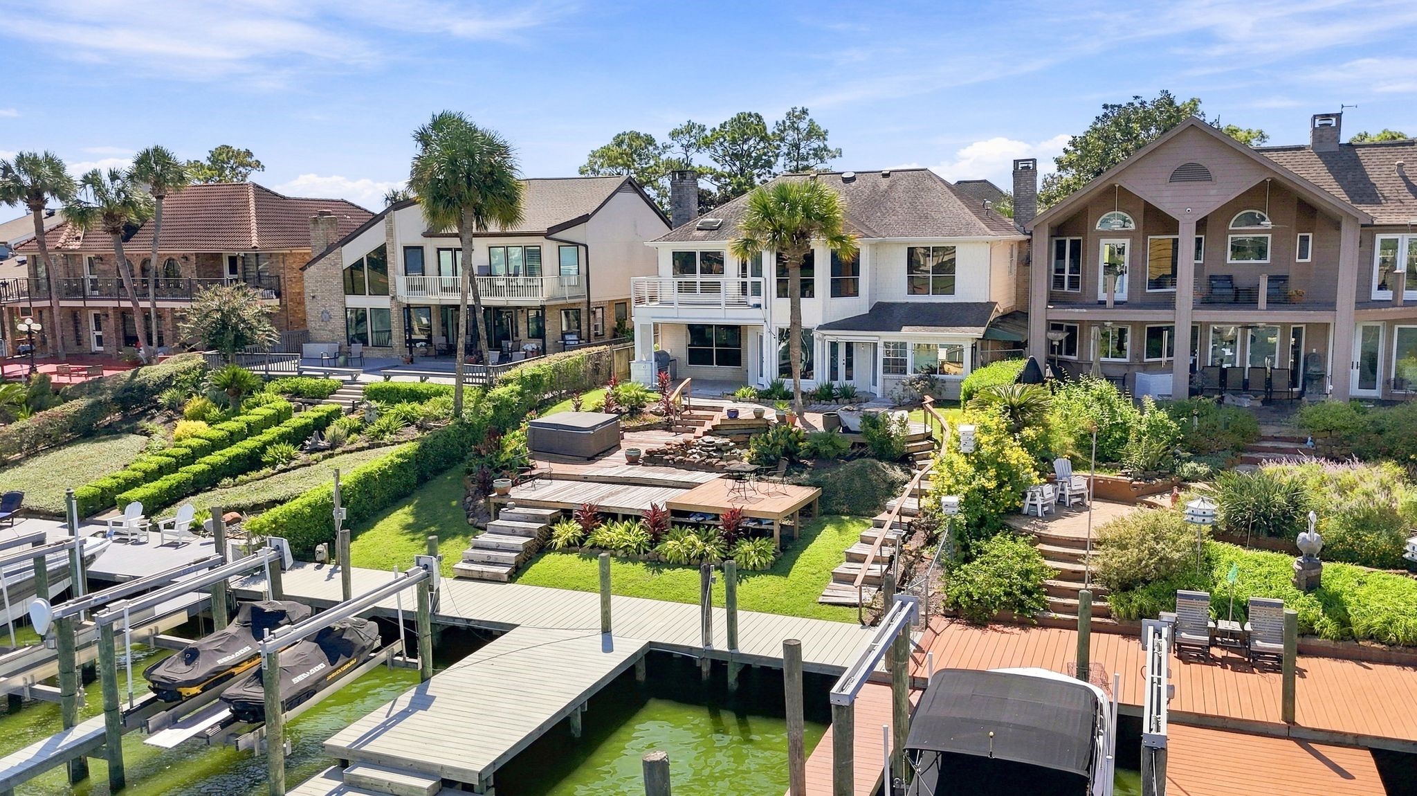 An aerial view shows the terraced backyard leading down to the private boat dock.