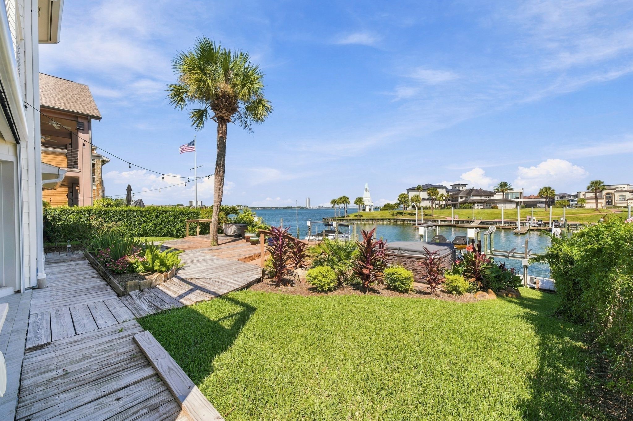 The backyard has a lush lawn and landscaping that leads down to the water.