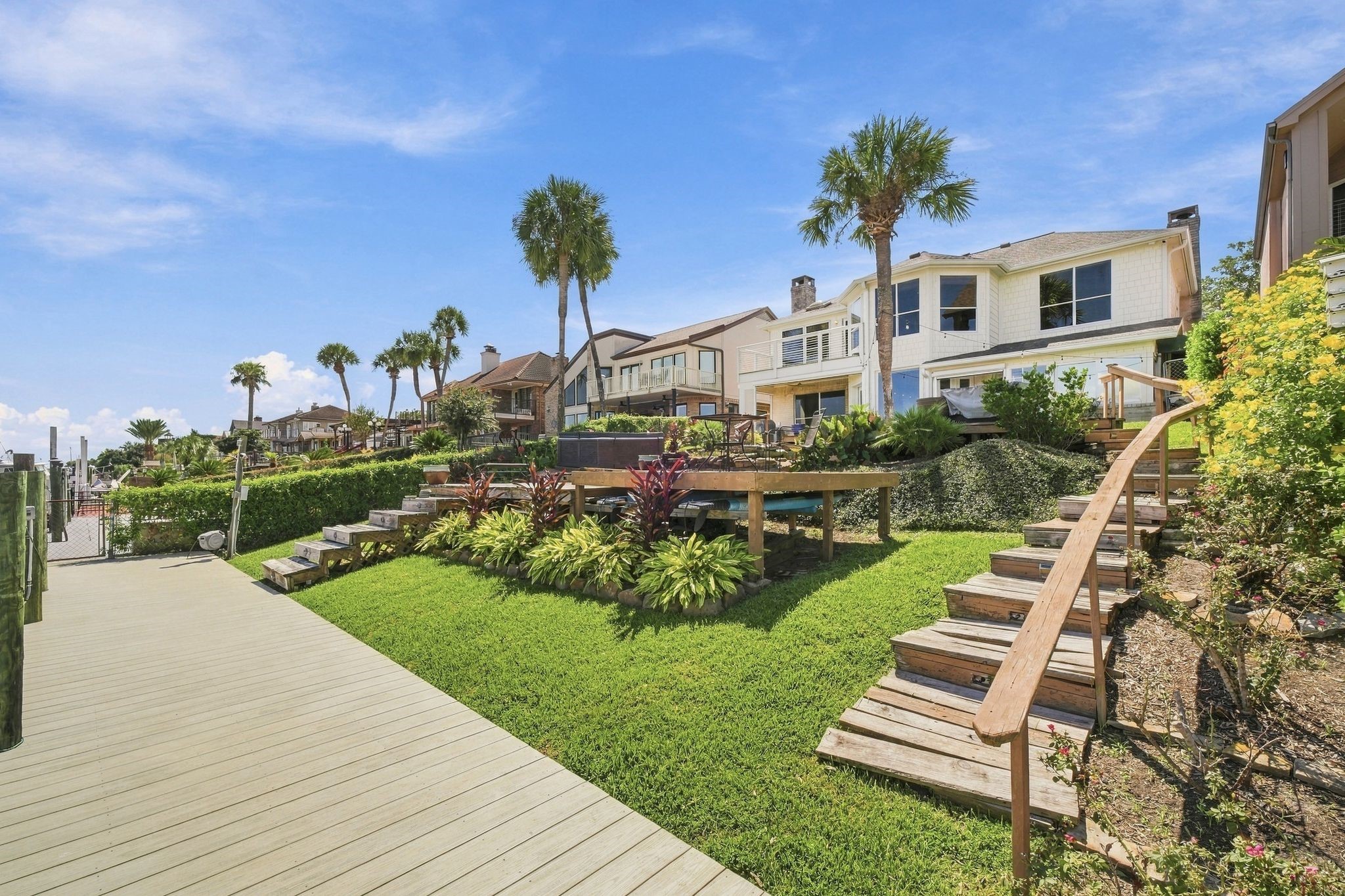 Terraced landscaping and wooden steps lead from the water up to the home.