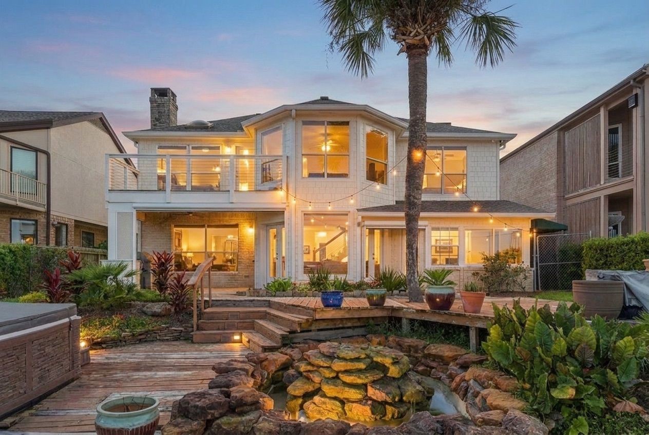 The back of the home features a rock waterfall, lush landscaping, and a private second-floor balcony overlooking the water. The back of the home features a rock waterfall, lush landscaping, and a private second-floor balcony overlooking the water.