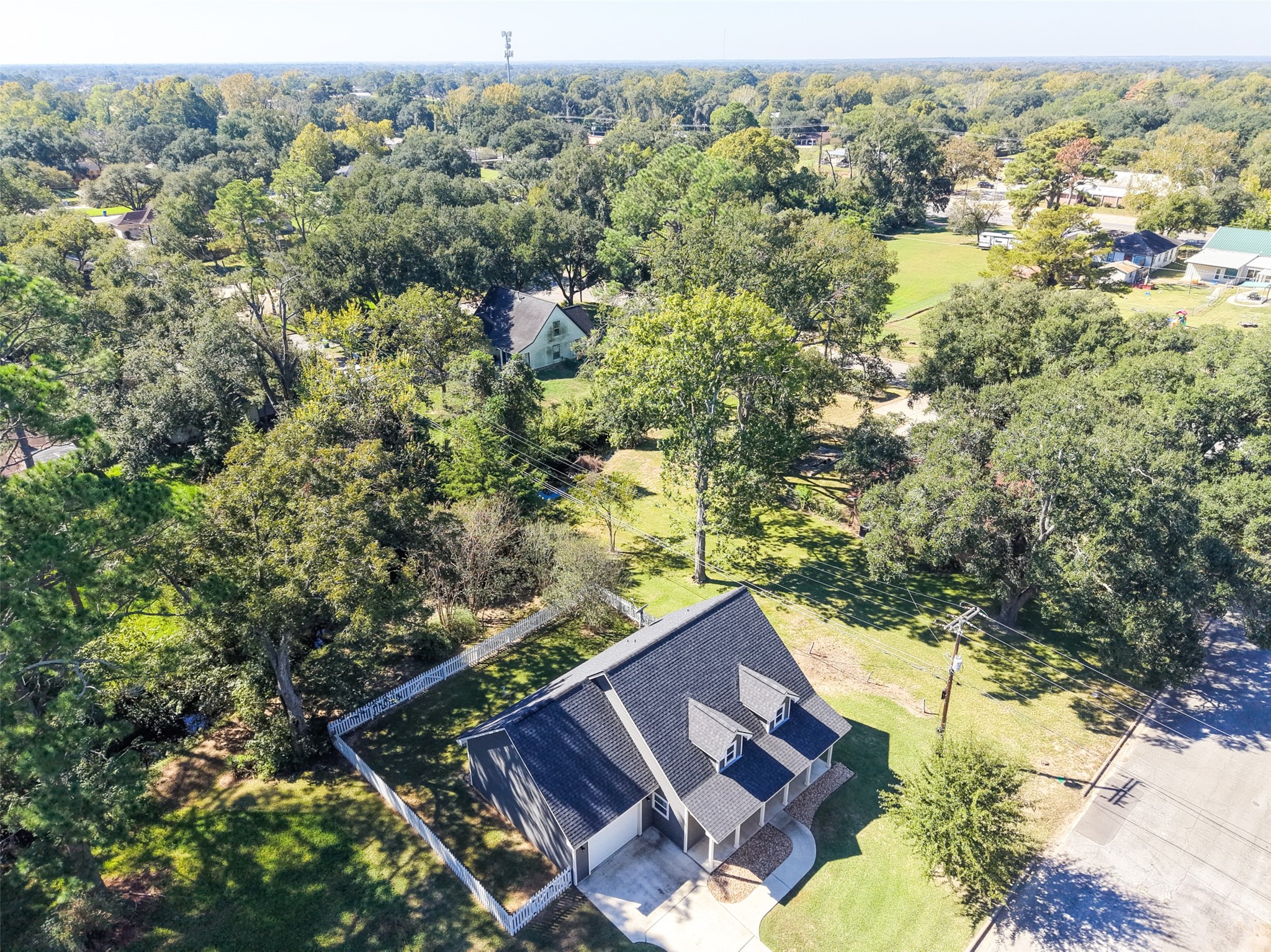 Aerial view highlighting the homes tree-lined setting, surrounding lawn, and nearby neighborhood.