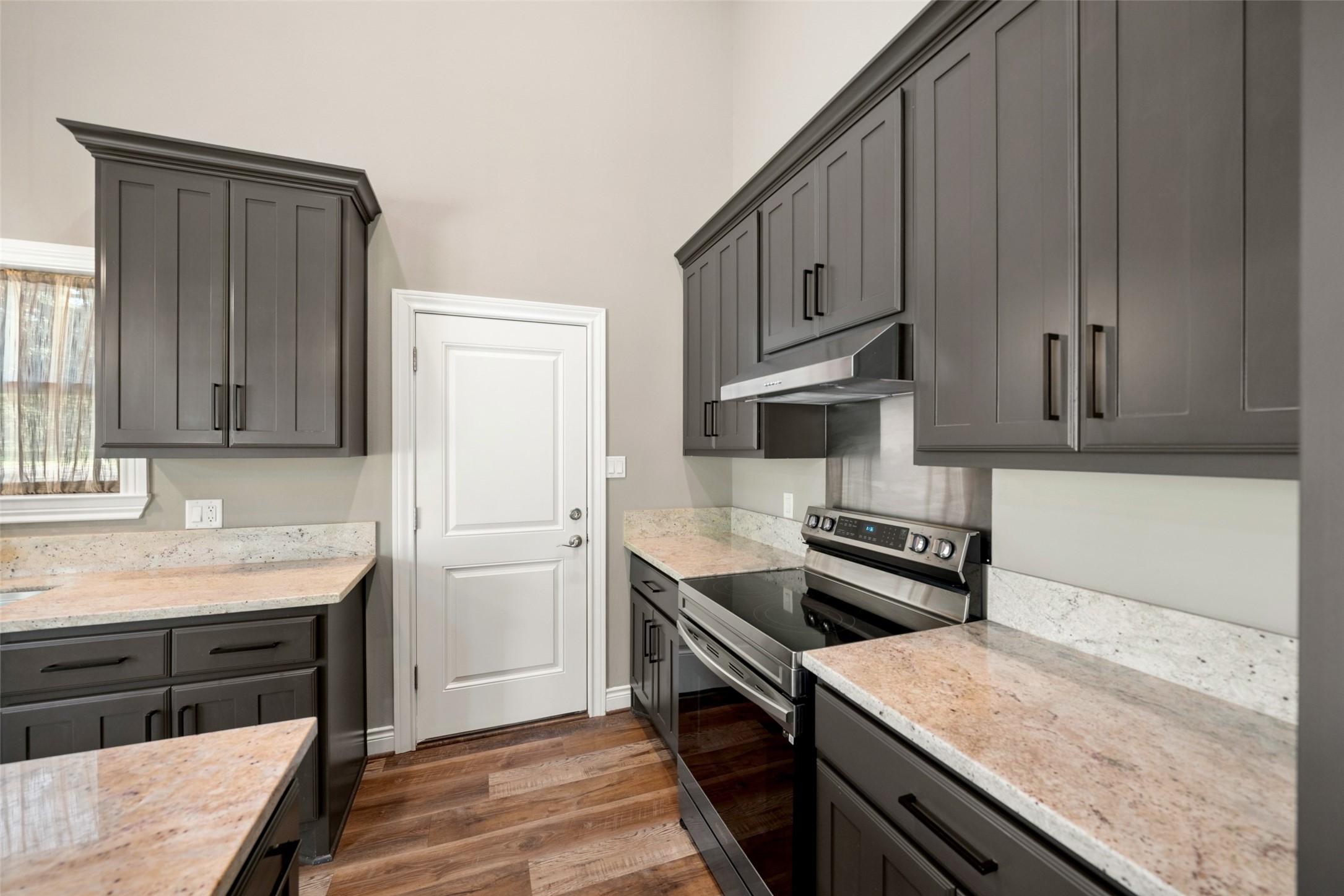 Kitchen featuring dark cabinetry, light countertops, stainless steel appliances, and wood-look flooring.