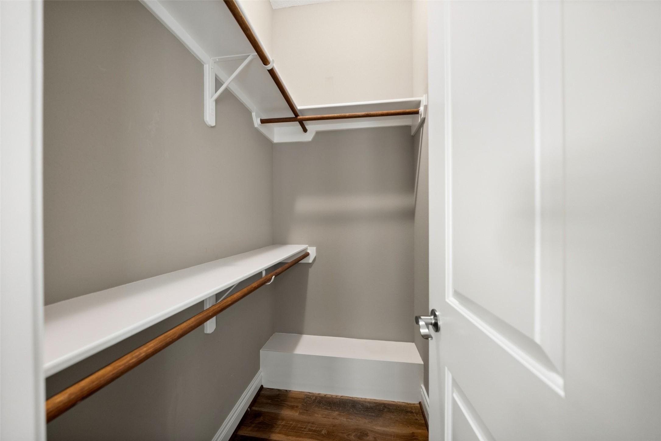 1. Walk-in closet featuring upper shelving, hanging rods, and wood-look flooring.