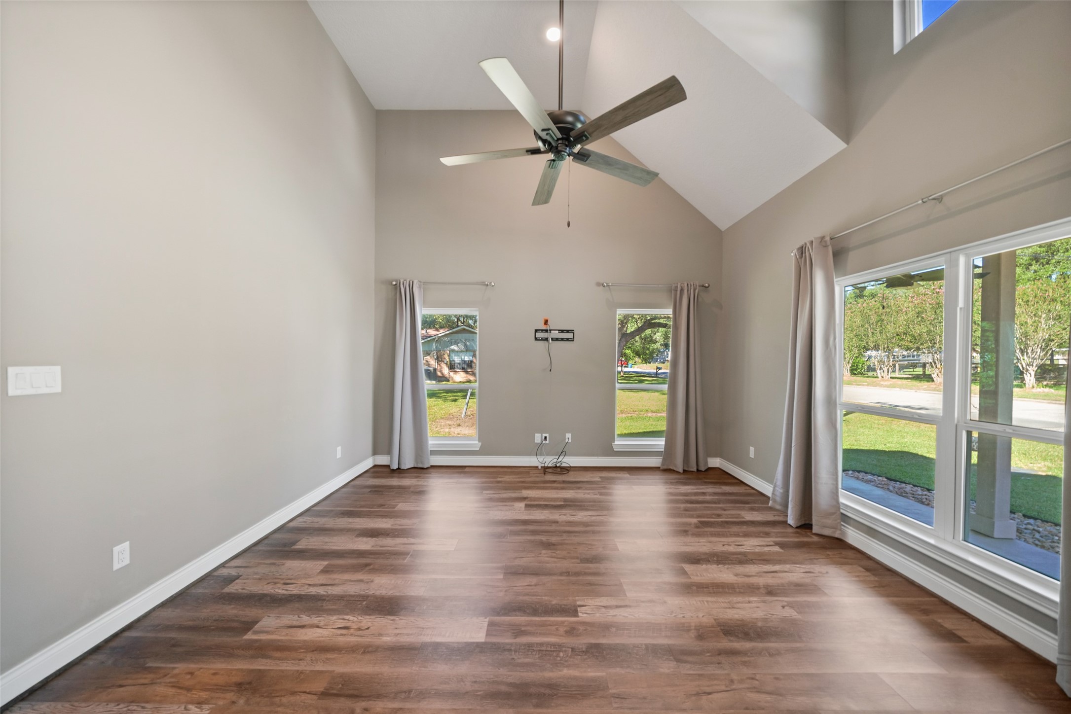 Living area featuring a vaulted ceiling, upper accent windows, and large windows with views of the fenced yard.