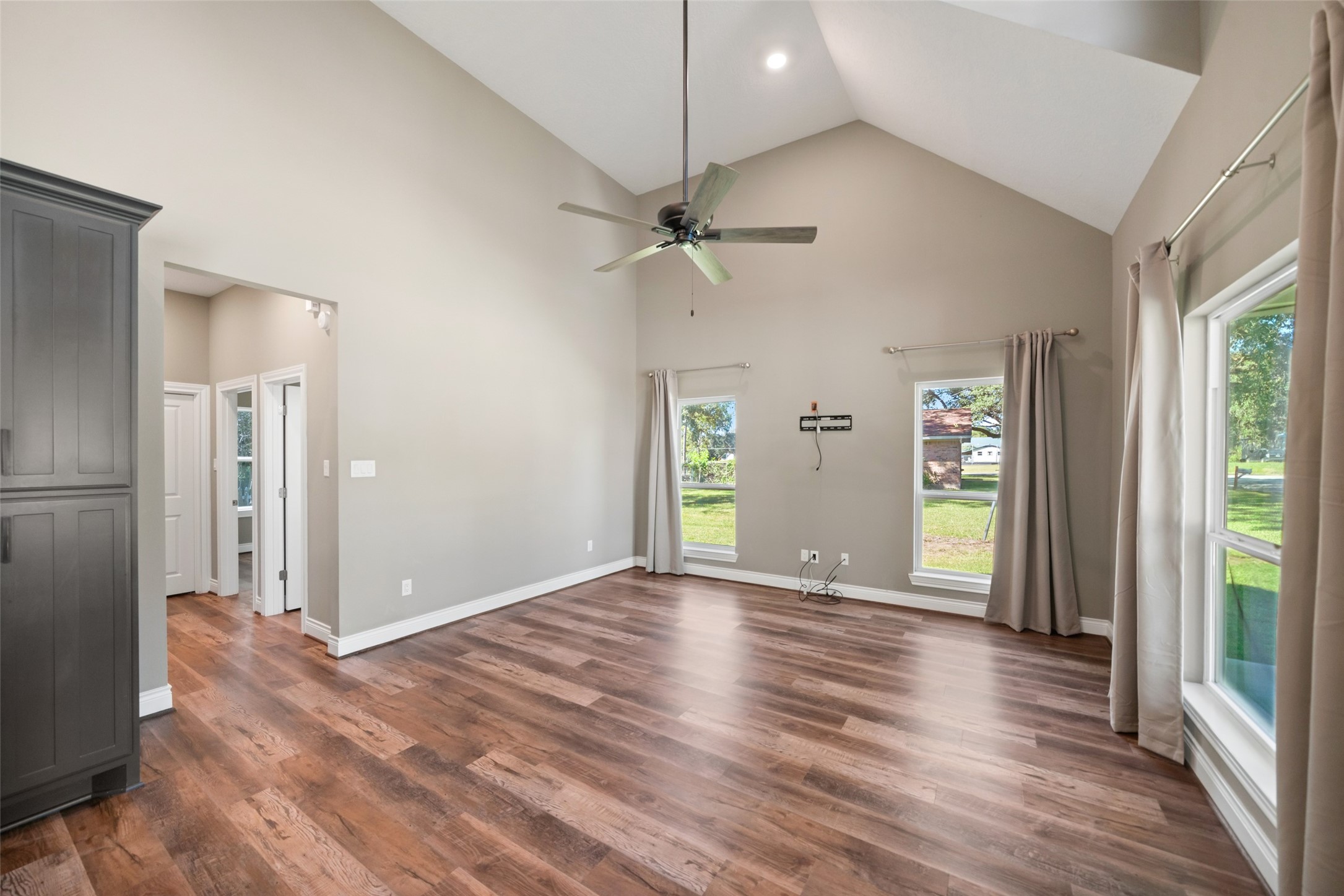 Alternate living area view showcasing the open layout, wood-look flooring, and connection to the kitchen.