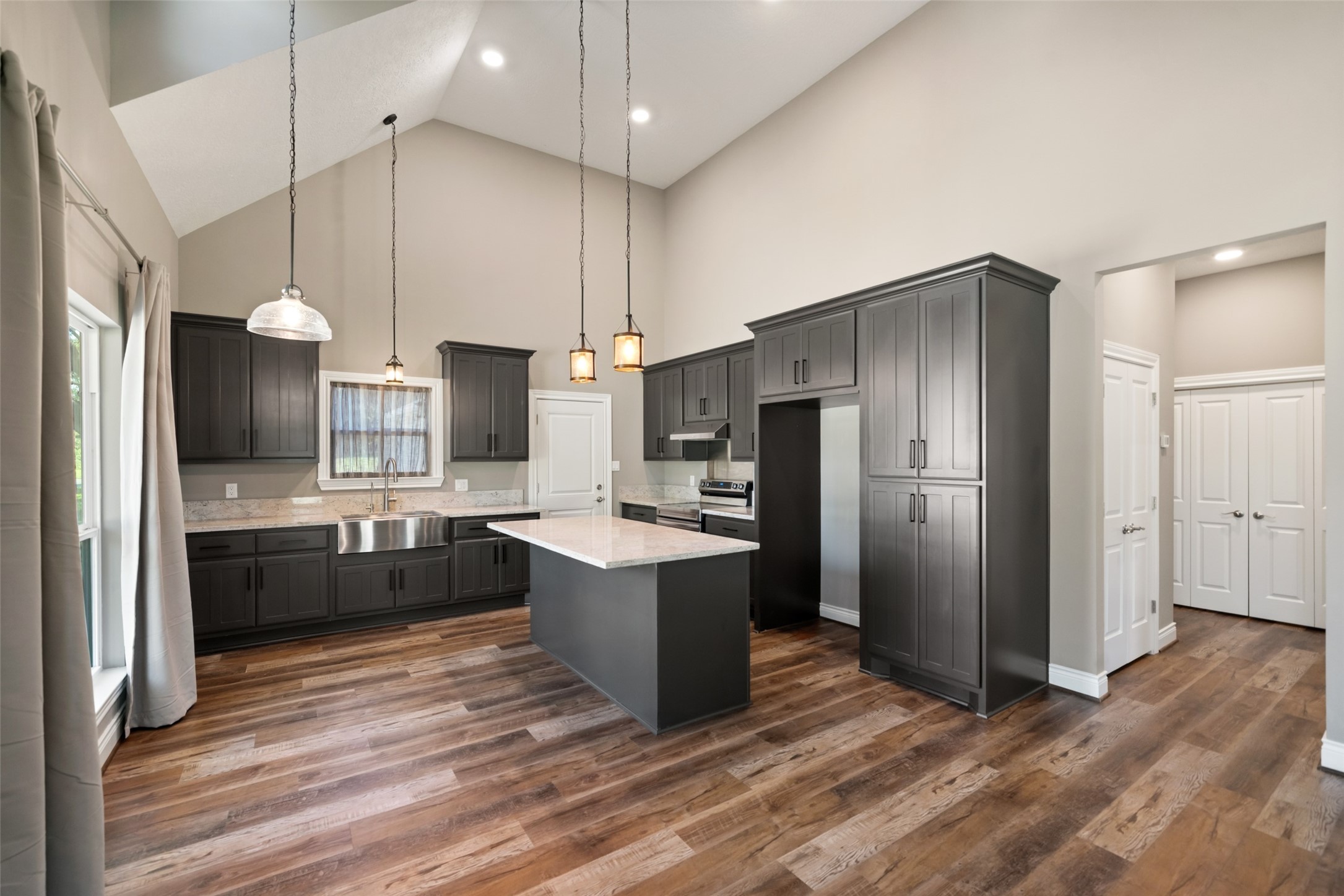 Kitchen featuring a center island, dark cabinetry, stainless steel appliances, pendant lighting, and a vaulted ceiling