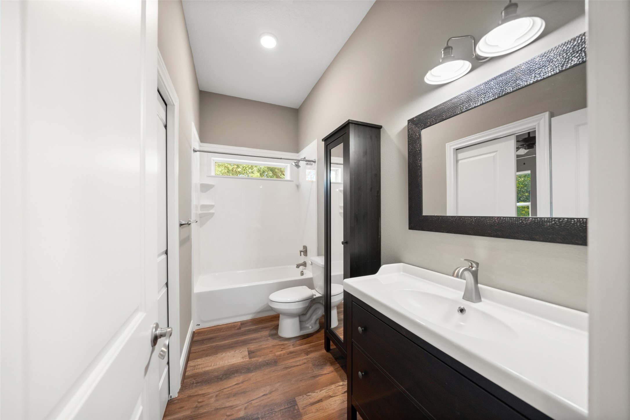 Bathroom featuring a long vanity with dark cabinetry, a framed mirror, and a tub/shower combination
