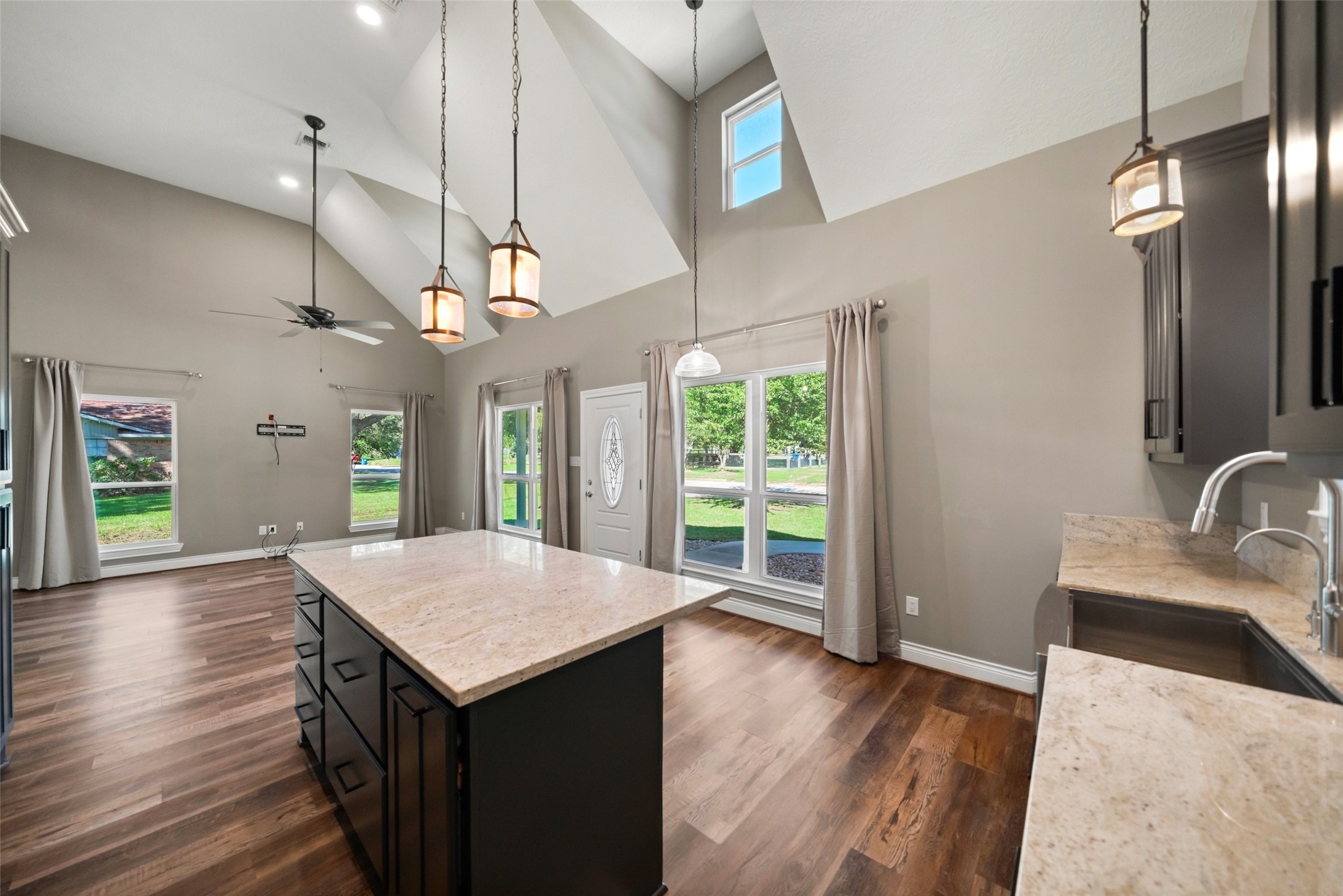 Open kitchen and living area featuring a center island with seating space, pendant lighting, and wood-look flooring throughout.