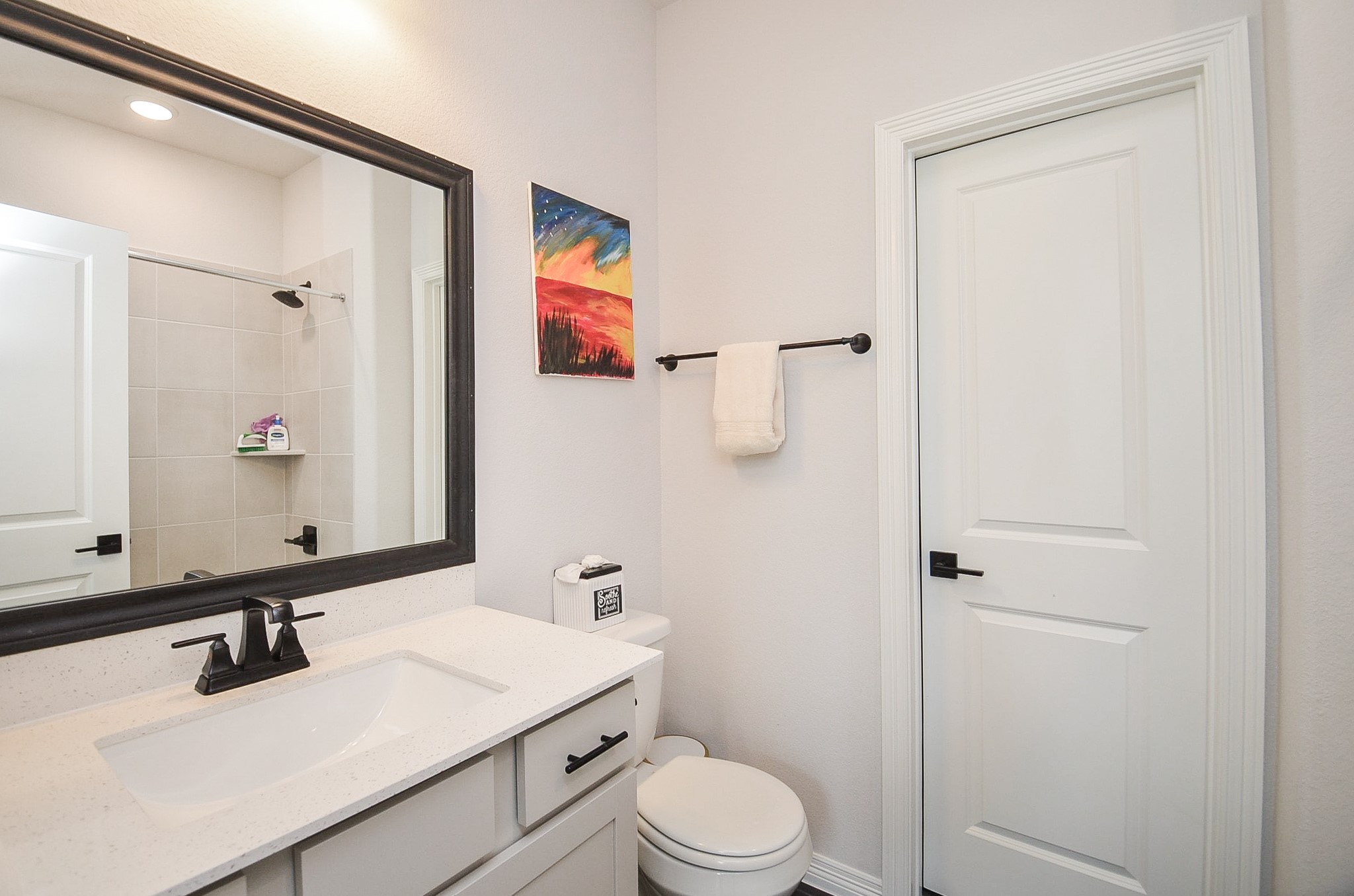 Modern bathroom featuring a sleek vanity with a large framed mirror, elegant fixtures, and a tiled shower for a contemporary touch.