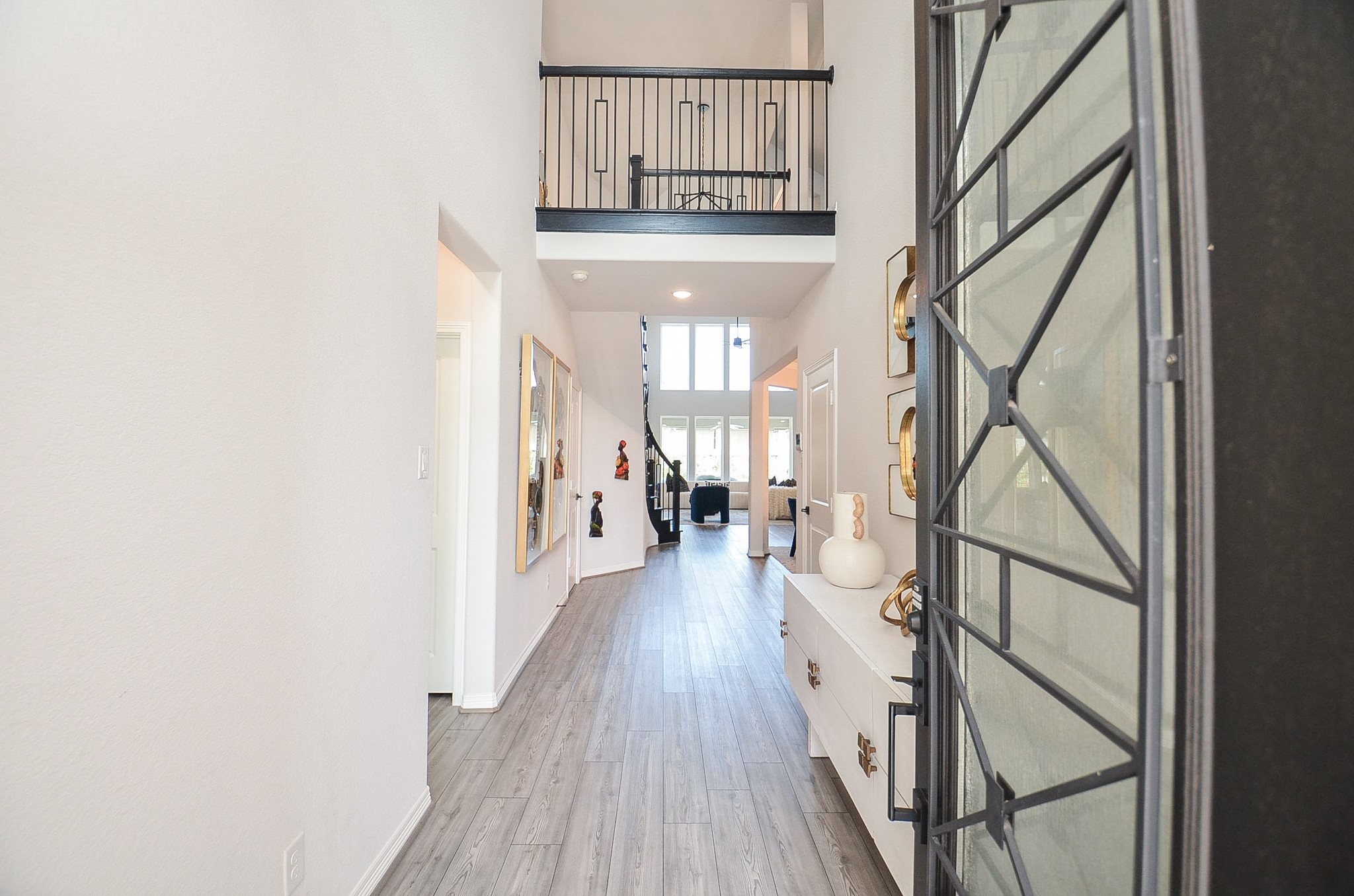 Bright and inviting entryway with high ceilings, modern decor, and sleek flooring leading to an open living area. Bright and inviting entryway with high ceilings, modern decor, and sleek flooring leading to an open living area.