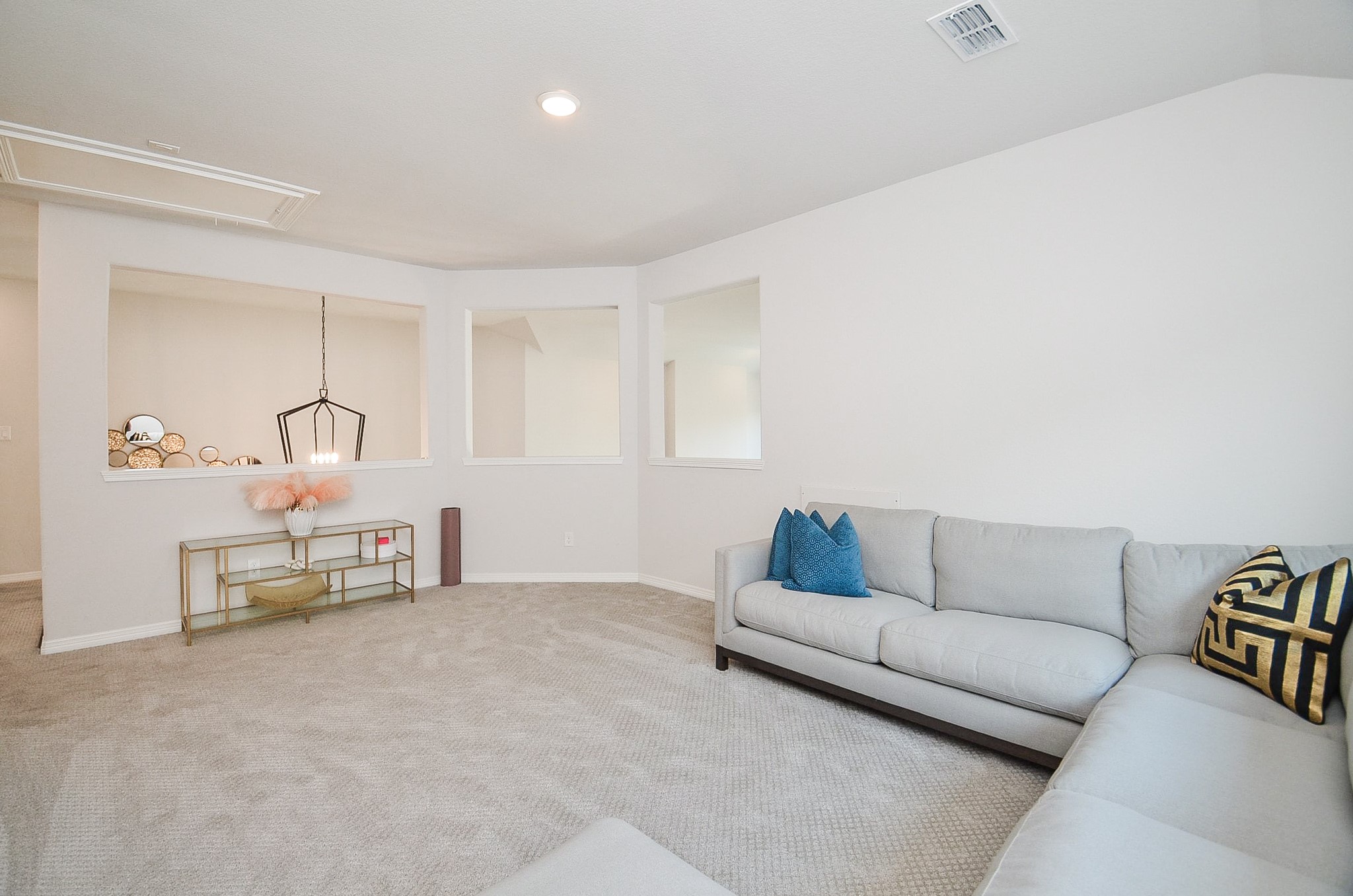 Spacious living area with plush carpeting, modern sectional sofa, and elegant decorative accents, offering a cozy and inviting atmosphere.