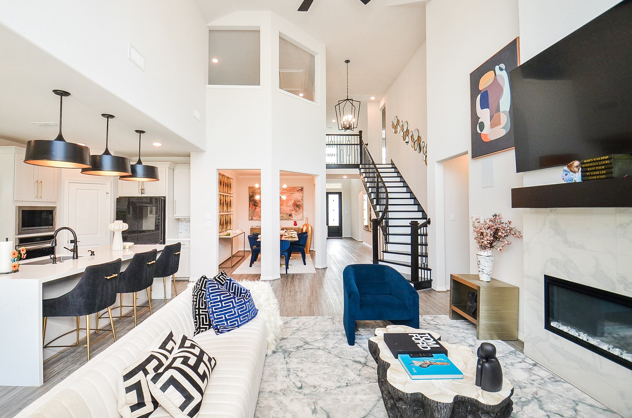 Stunning open-concept living space featuring soaring ceilings, a modern kitchen with chic pendant lighting, and a cozy fireplace. The elegant staircase leads to a second level, while the dining area is perfect for entertaining.