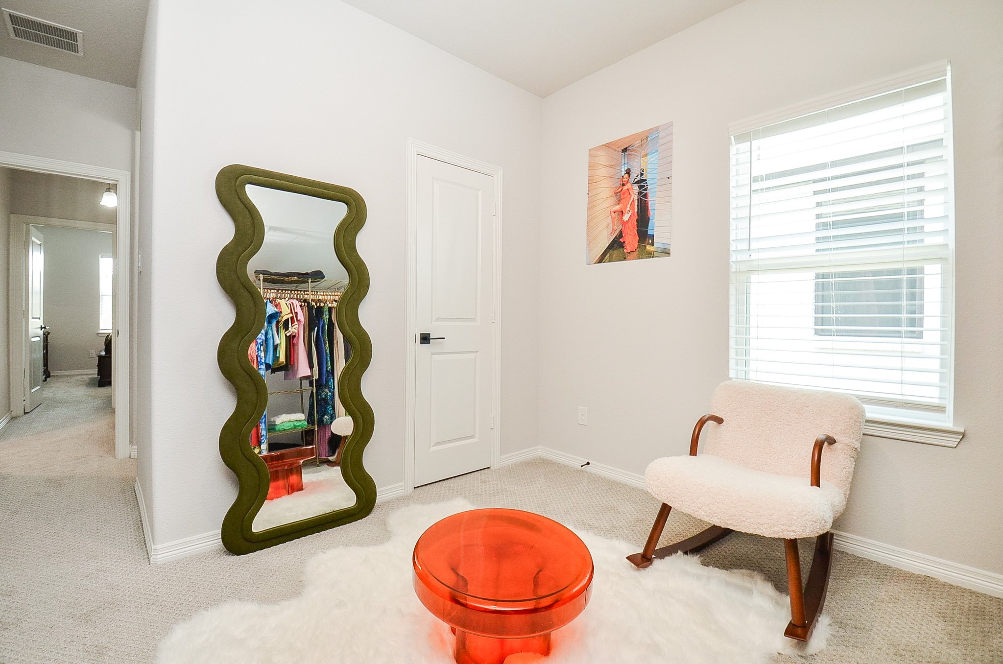 Chic and cozy corner features a stylish wave mirror, plush chair, and vibrant decor, creating a welcoming and modern atmosphere.