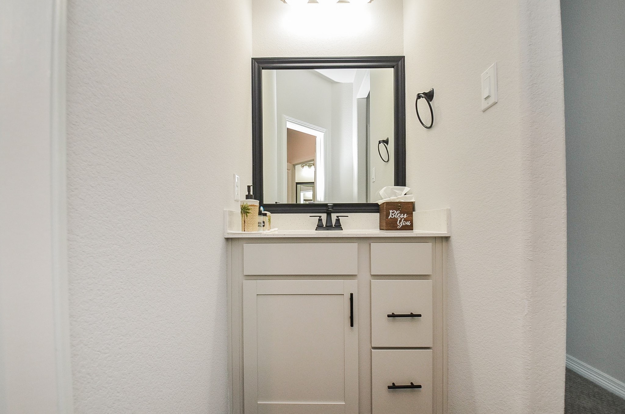 Charming powder room with a sleek vanity, modern fixtures, and a stylish framed mirror.