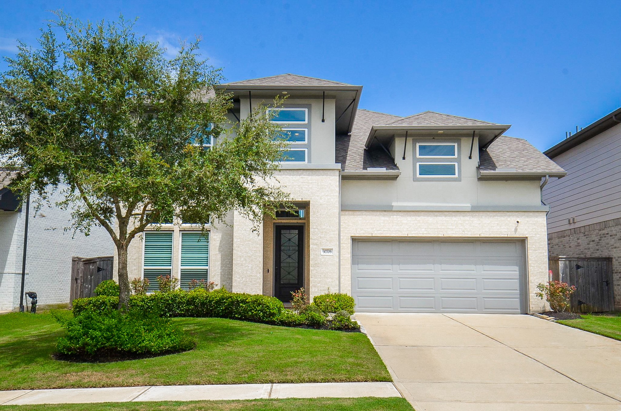 Modern two-story home with a sleek facade, featuring a spacious two-car garage and well-maintained landscaping.