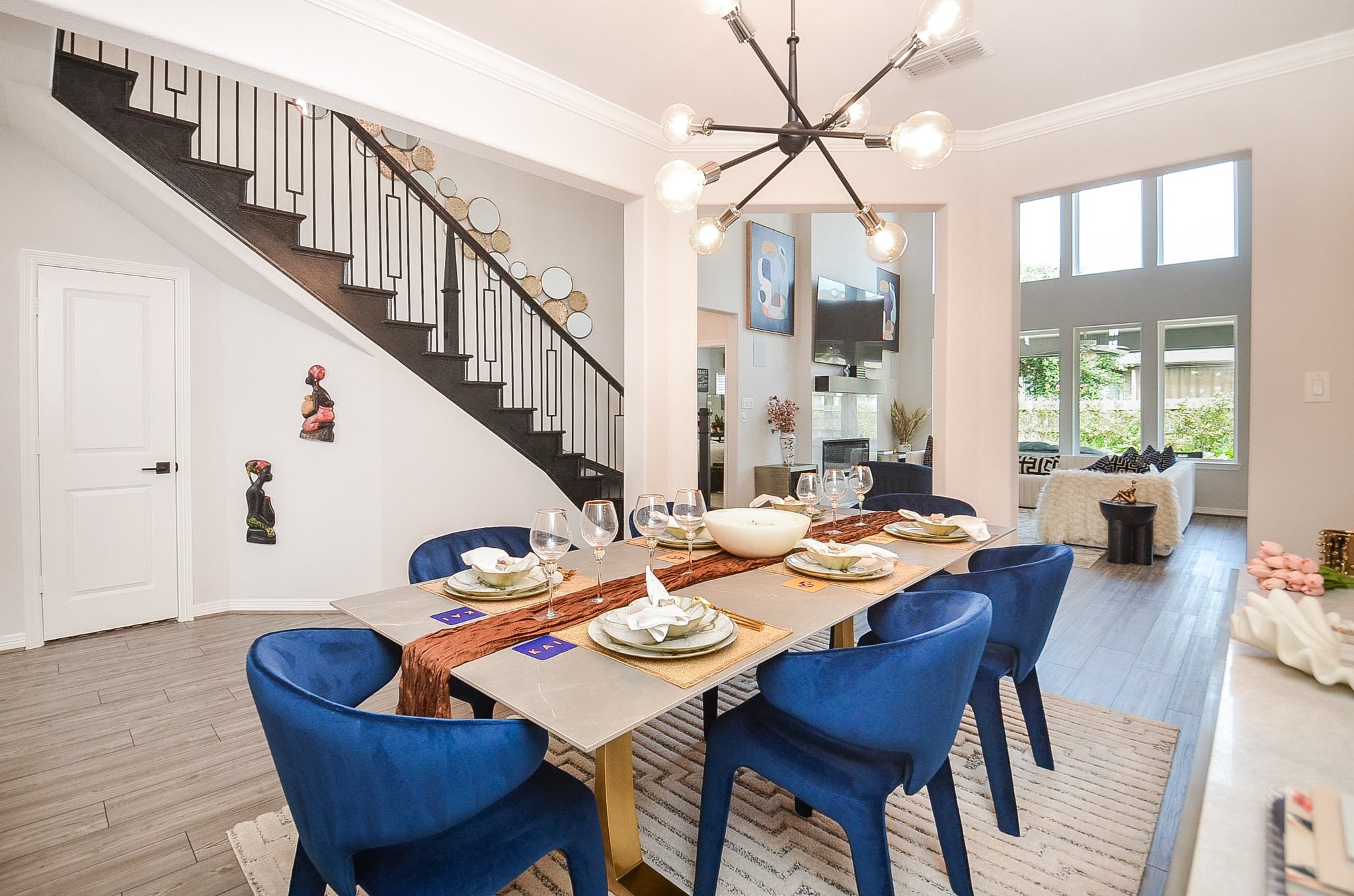 Elegant dining area that seamlessly connects to the bright living room with large windows and a view of the staircase.